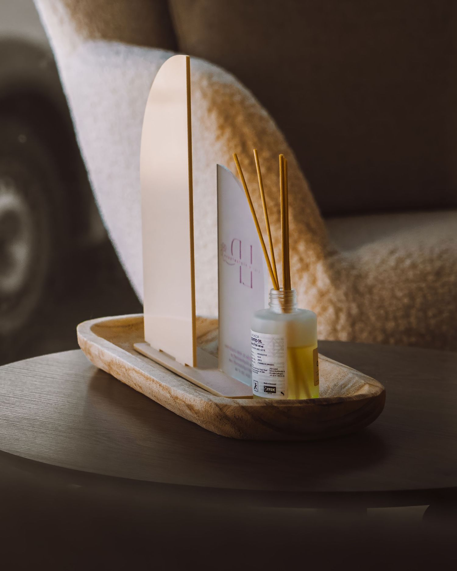 Wooden phone stand holder with small bottle sitting on table in soft lighting.