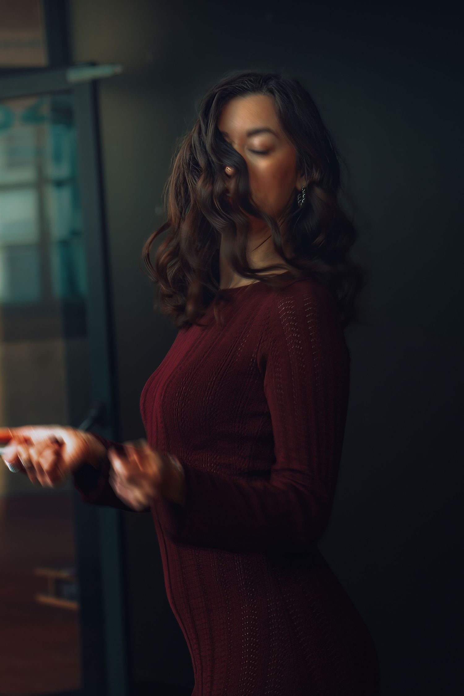 A person in a burgundy sweater moves through a series of artistic dance poses in moody lighting.