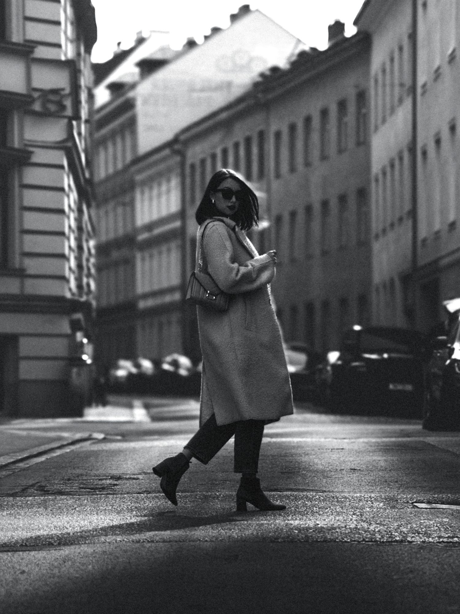 Street photography of legs walking on cobblestone street in classic European architecture setting.