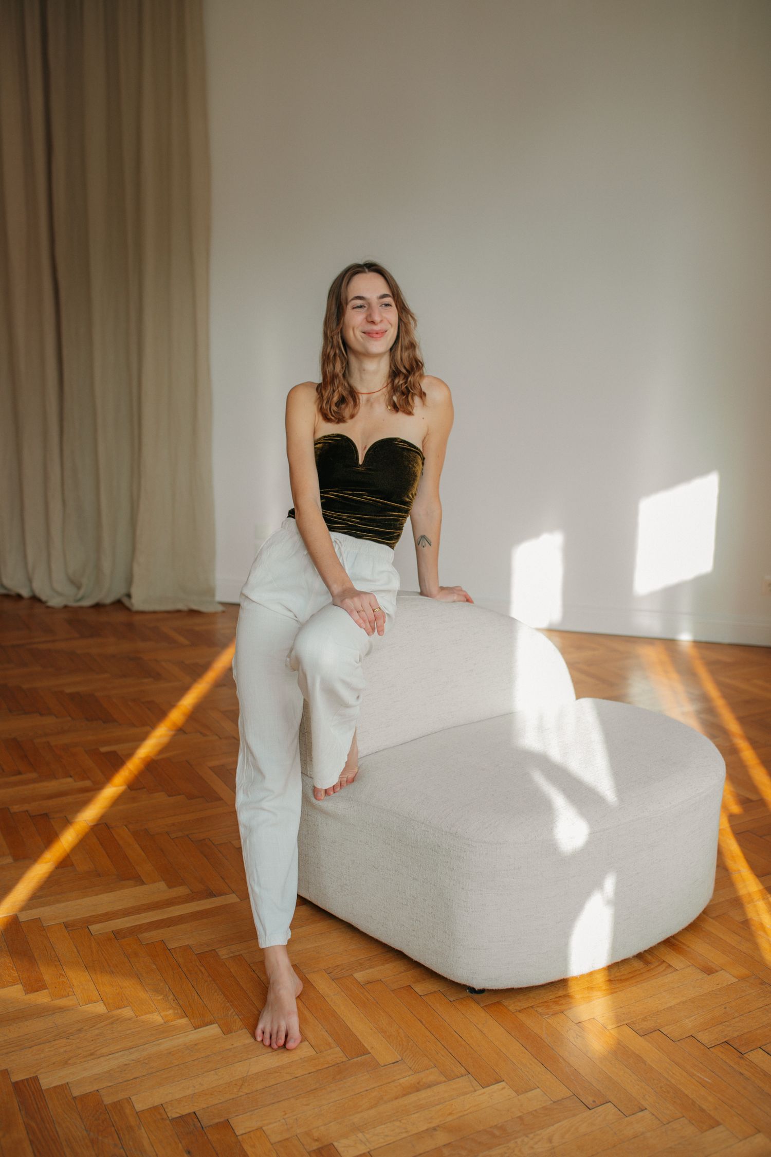 A series of photos showing someone in a black top and white pants posing on a white couch with sunlight streaming in.