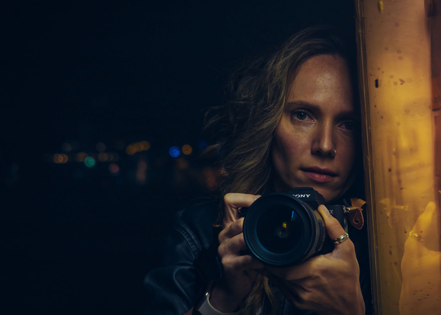 Camera lens reflecting in dark moody lighting creates an artistic self-portrait effect.