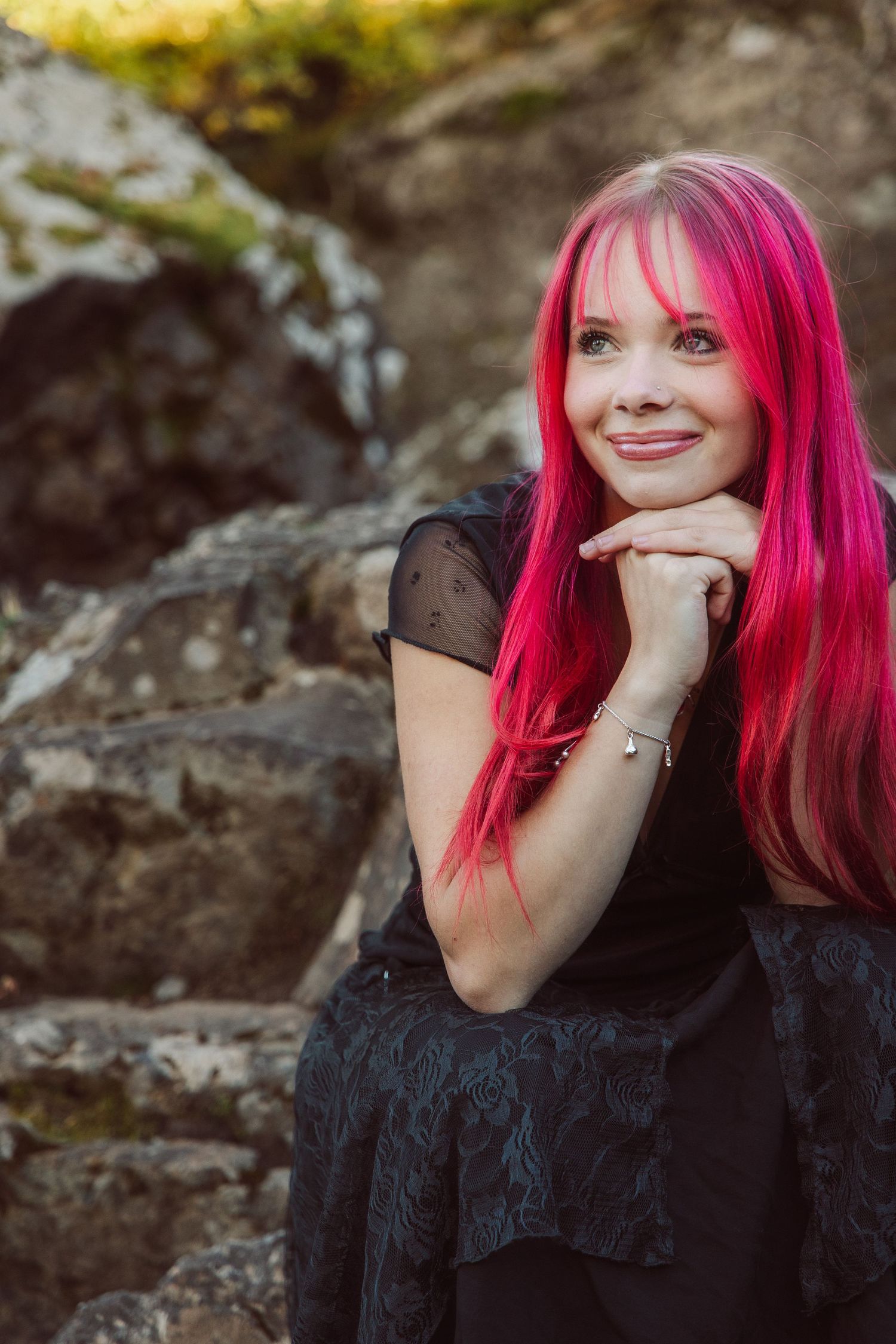 A series of photos showing someone with vibrant pink hair wearing black clothing against a rocky background.