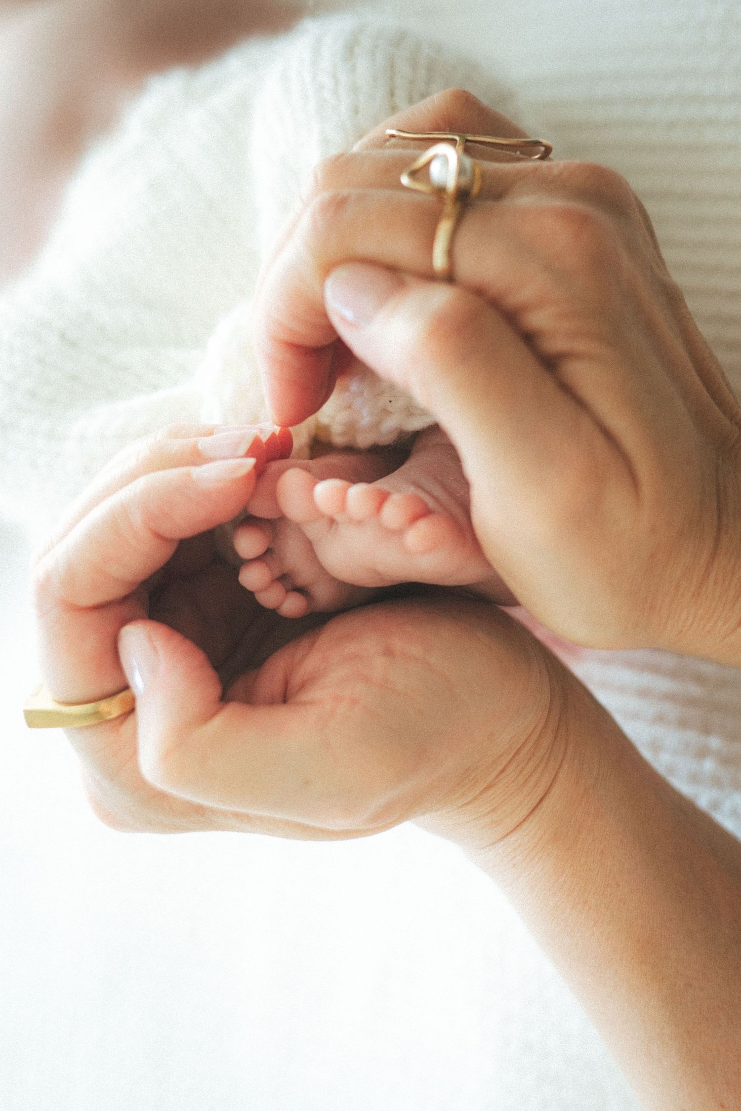 Close-up photos of gentle hands holding and caressing tiny baby feet.