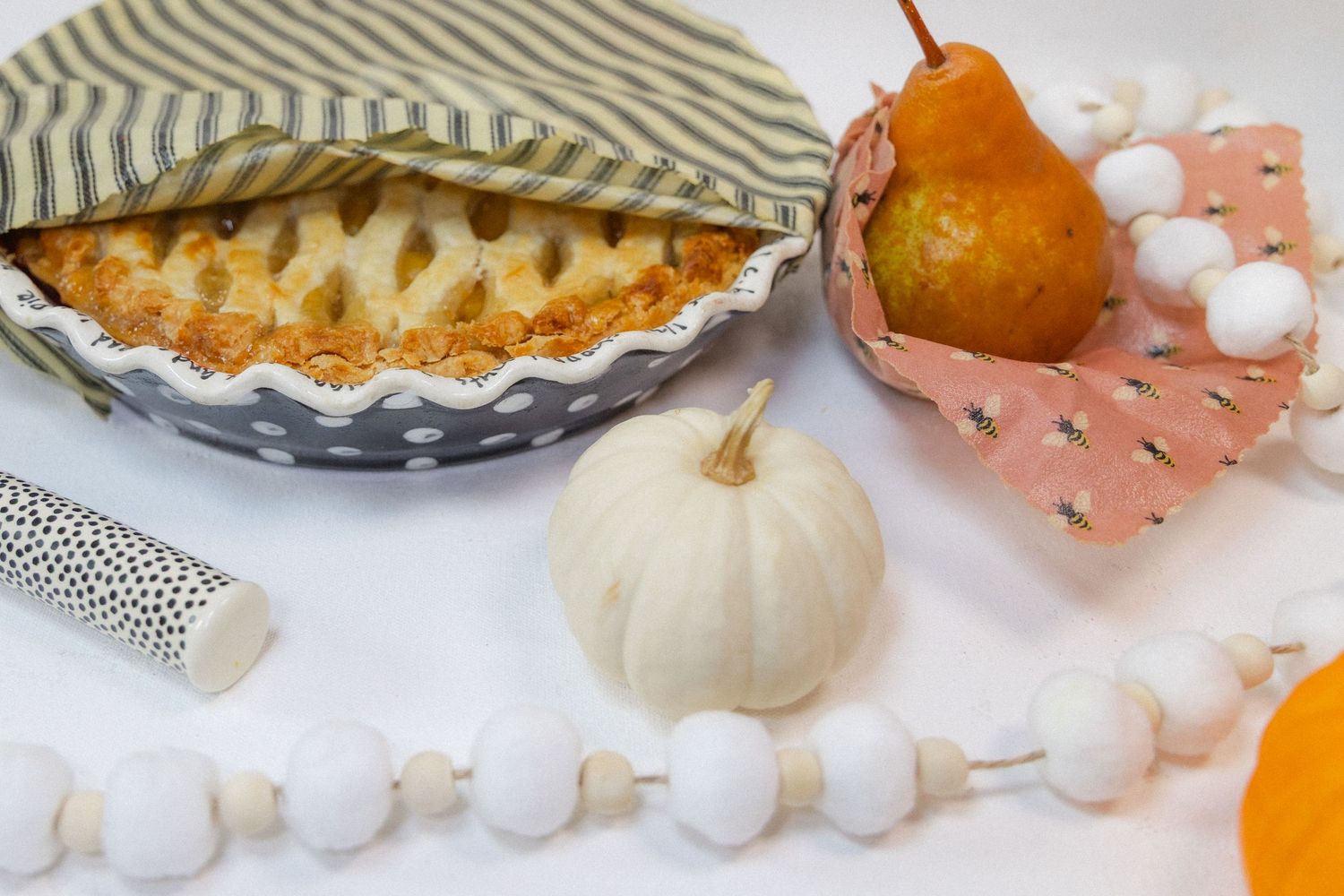 A collection of fall-themed decorative items including pumpkins, pies, and white beaded garlands arranged on a surface.
