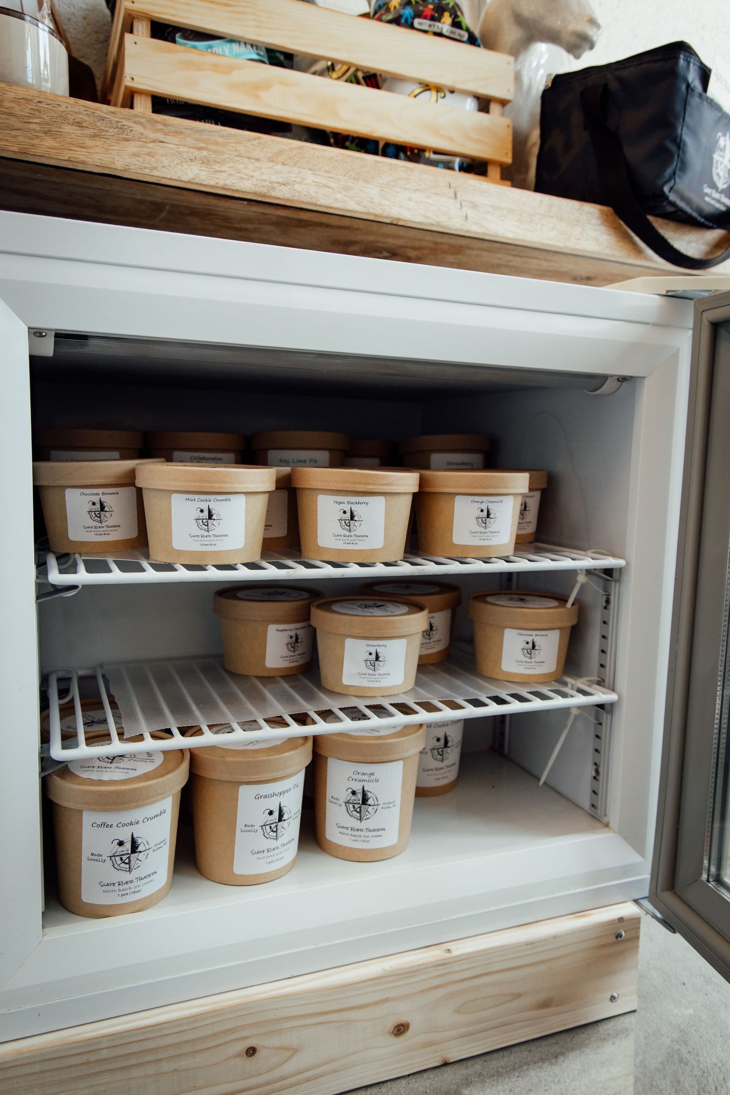 Freezer stocked with labeled kraft paper containers on wire shelves, organized food storage solution.