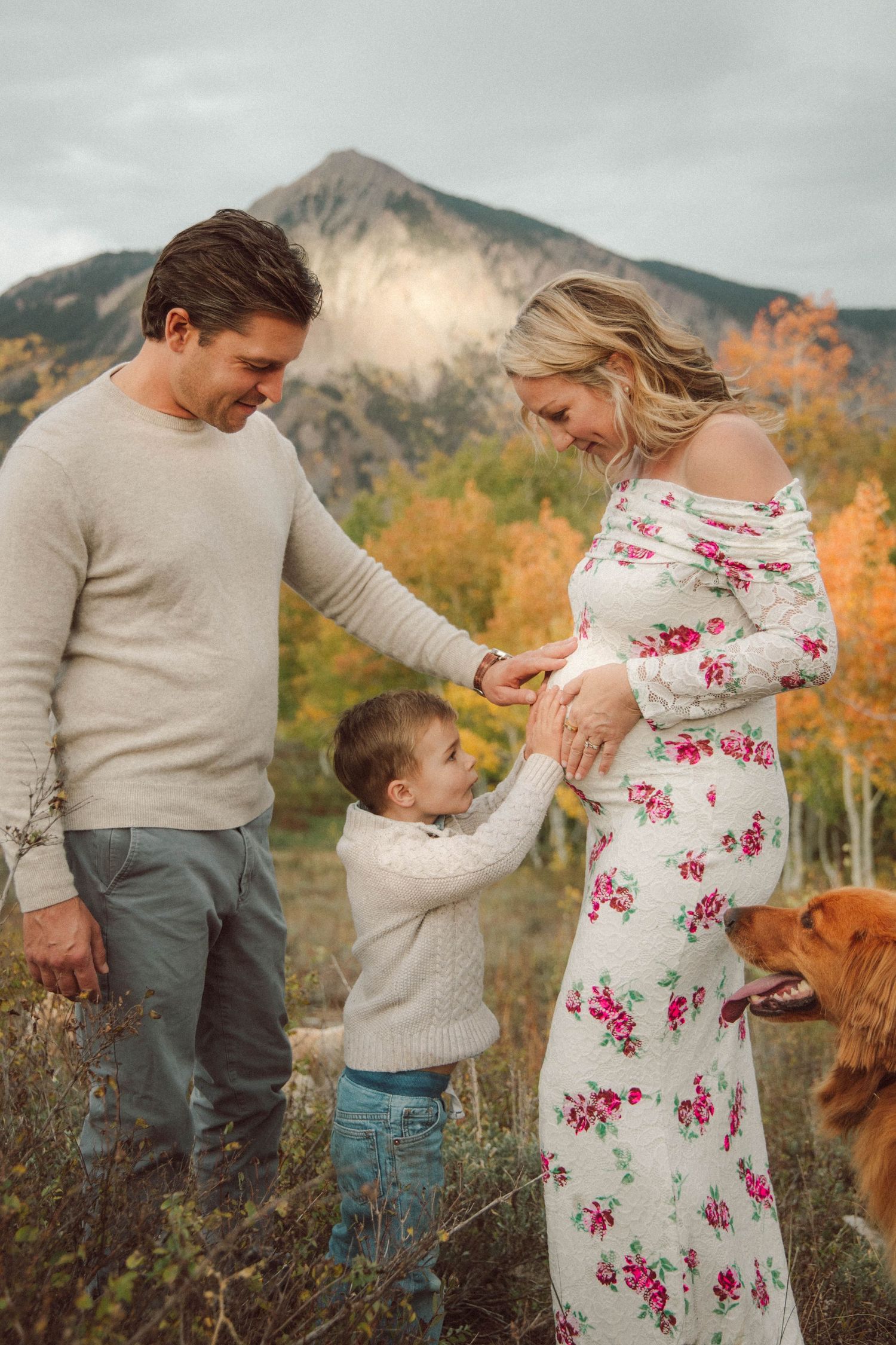 A family shares tender moments together against a backdrop of autumn mountains and golden foliage.