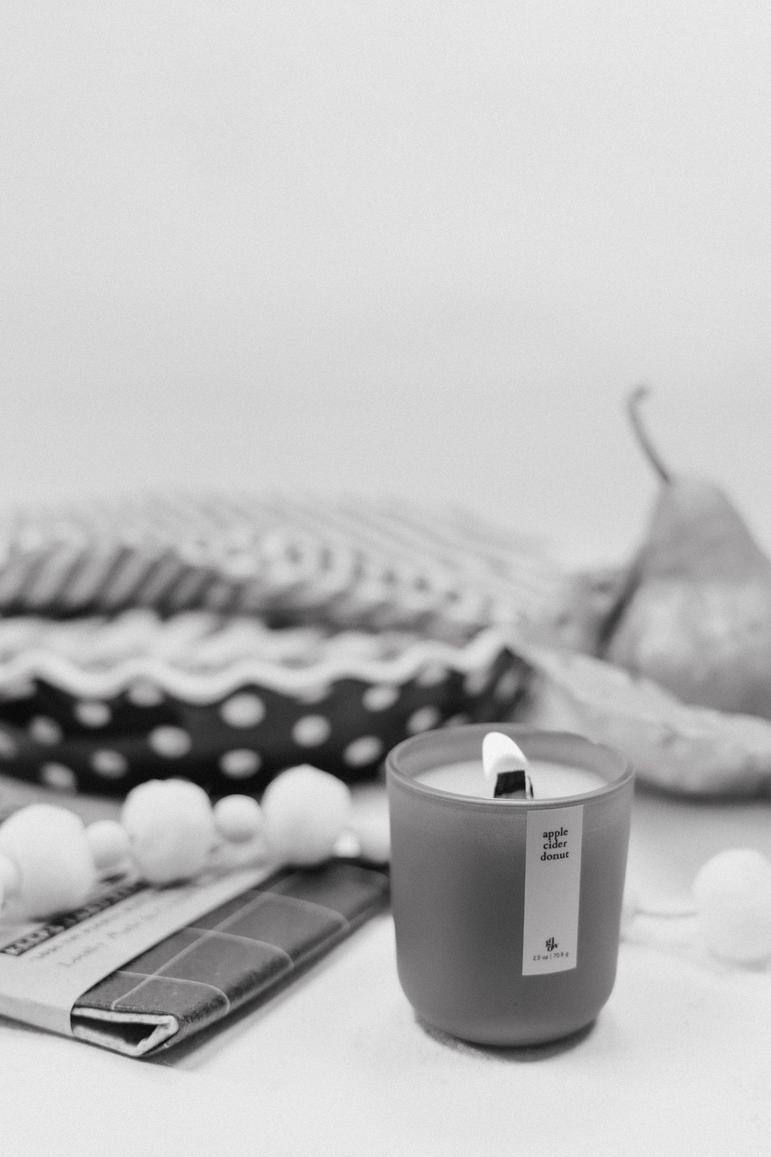 Minimalist monochrome composition with candles and decorative items arranged on a white surface.