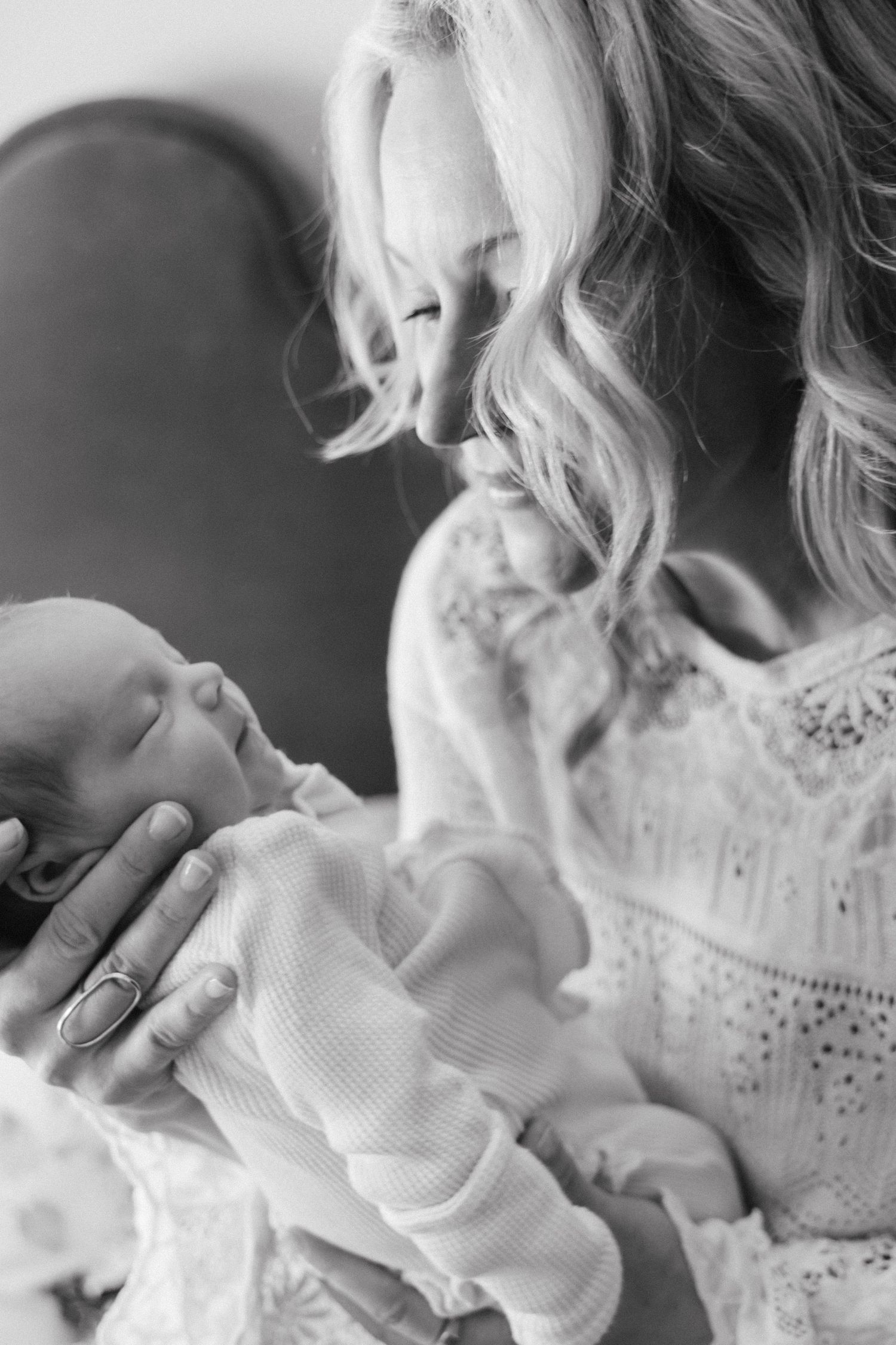 Black and white photo series showing tender moments between parent and baby in white knit clothing.