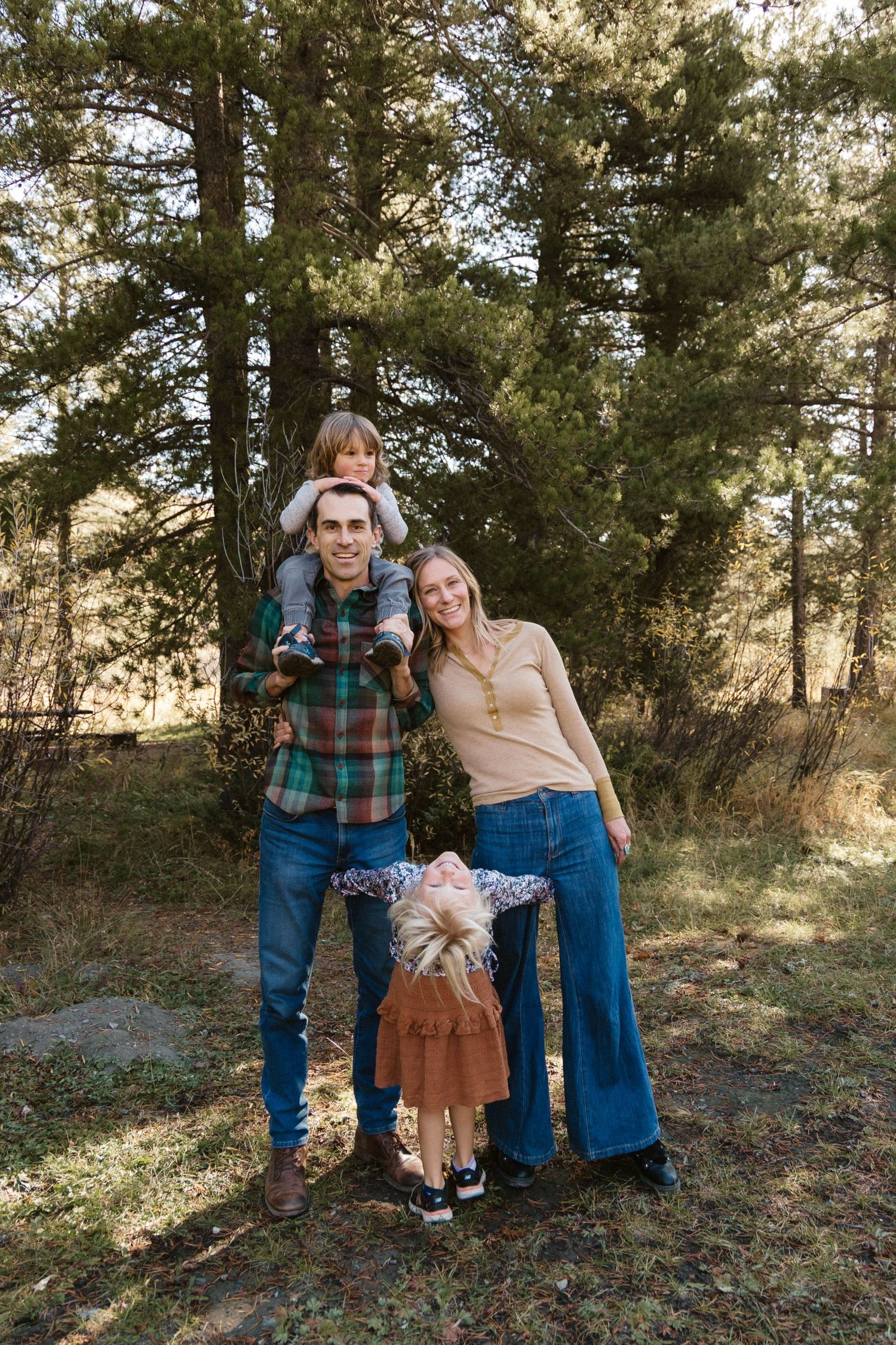 A family poses together for a portrait in a wooded outdoor setting on an autumn day.
