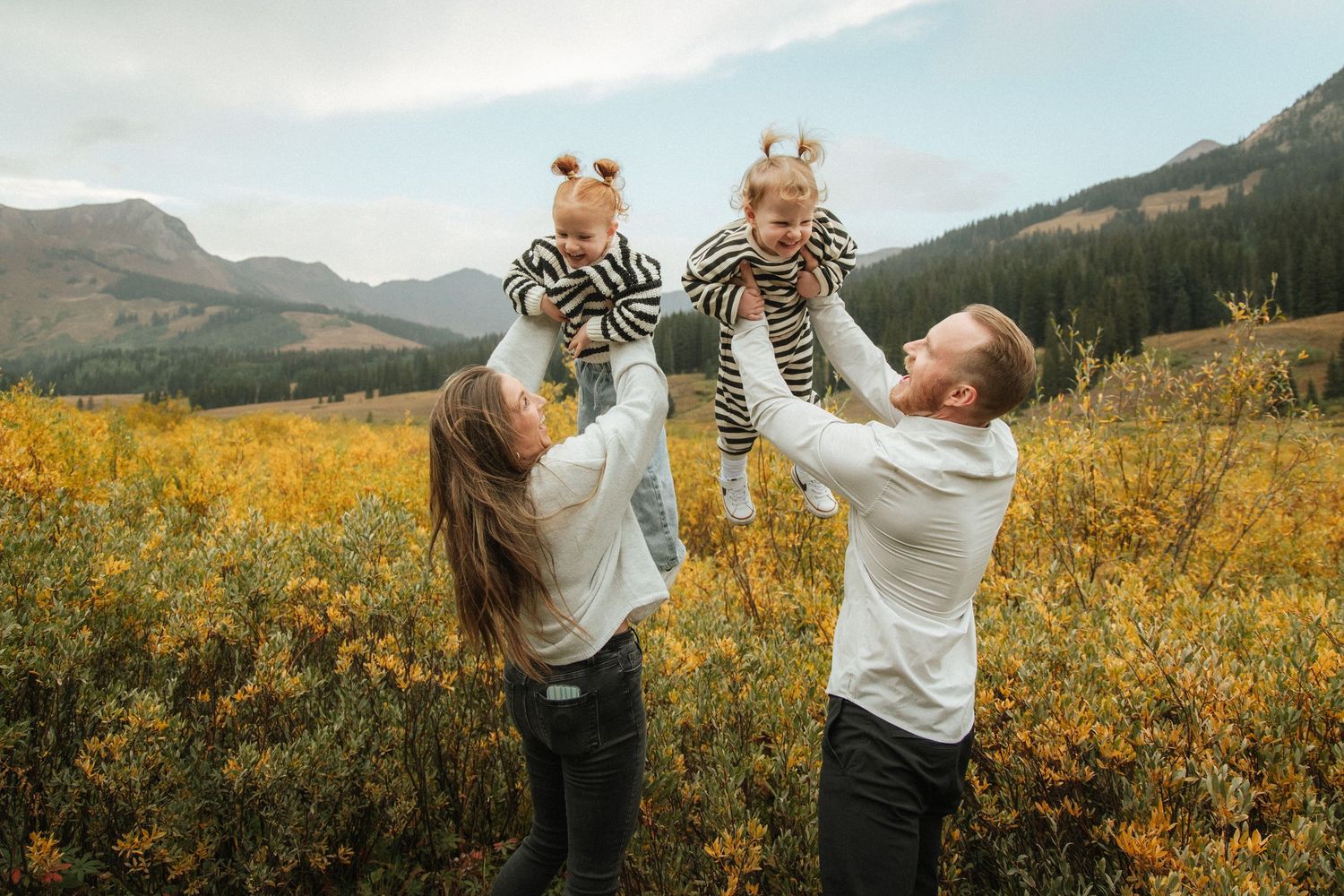 Playful family photos in a mountain meadow filled with yellow wildflowers.