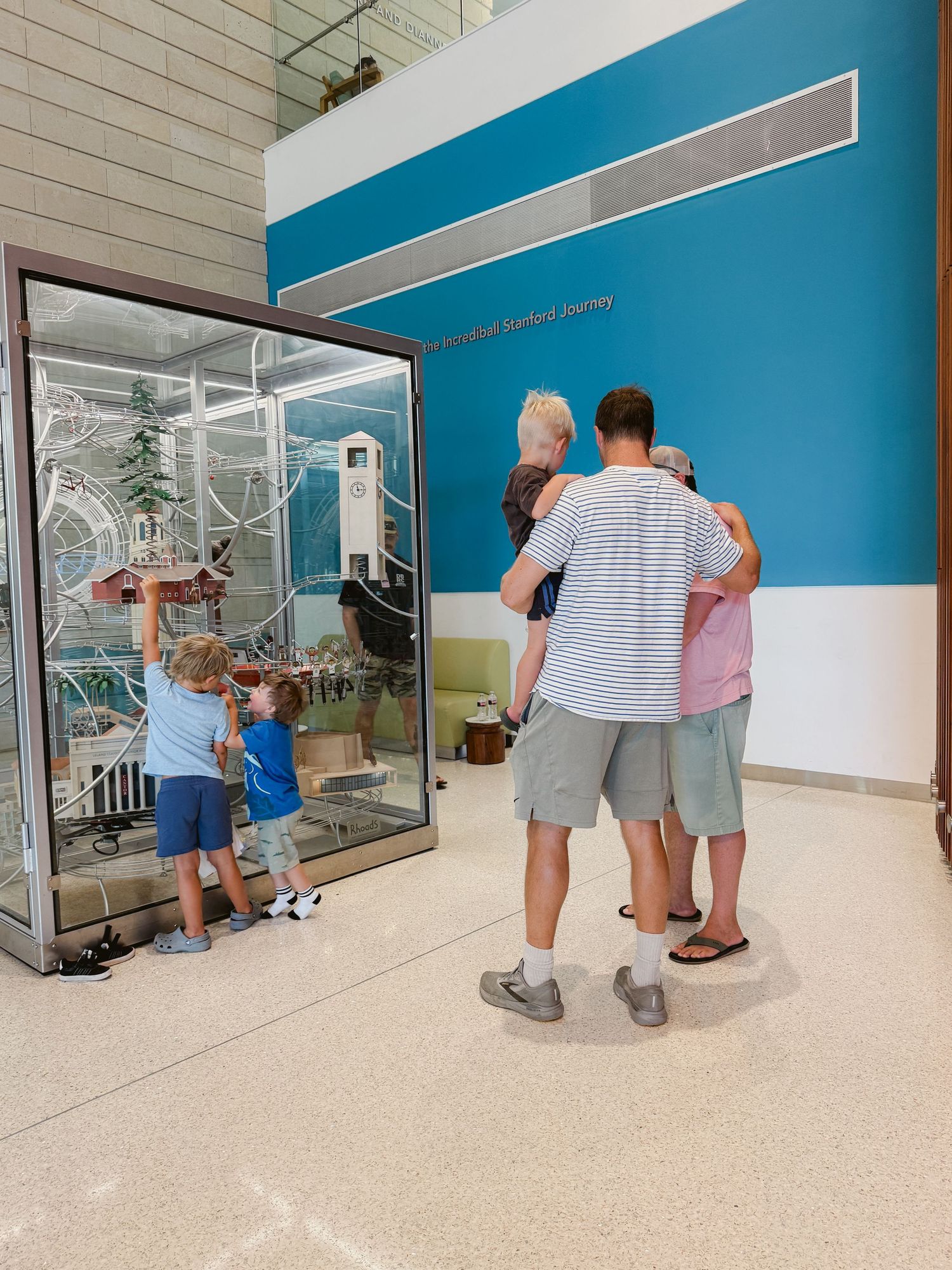 Family exploring a glass display exhibit at a museum, with children touching the case and adults standing nearby.