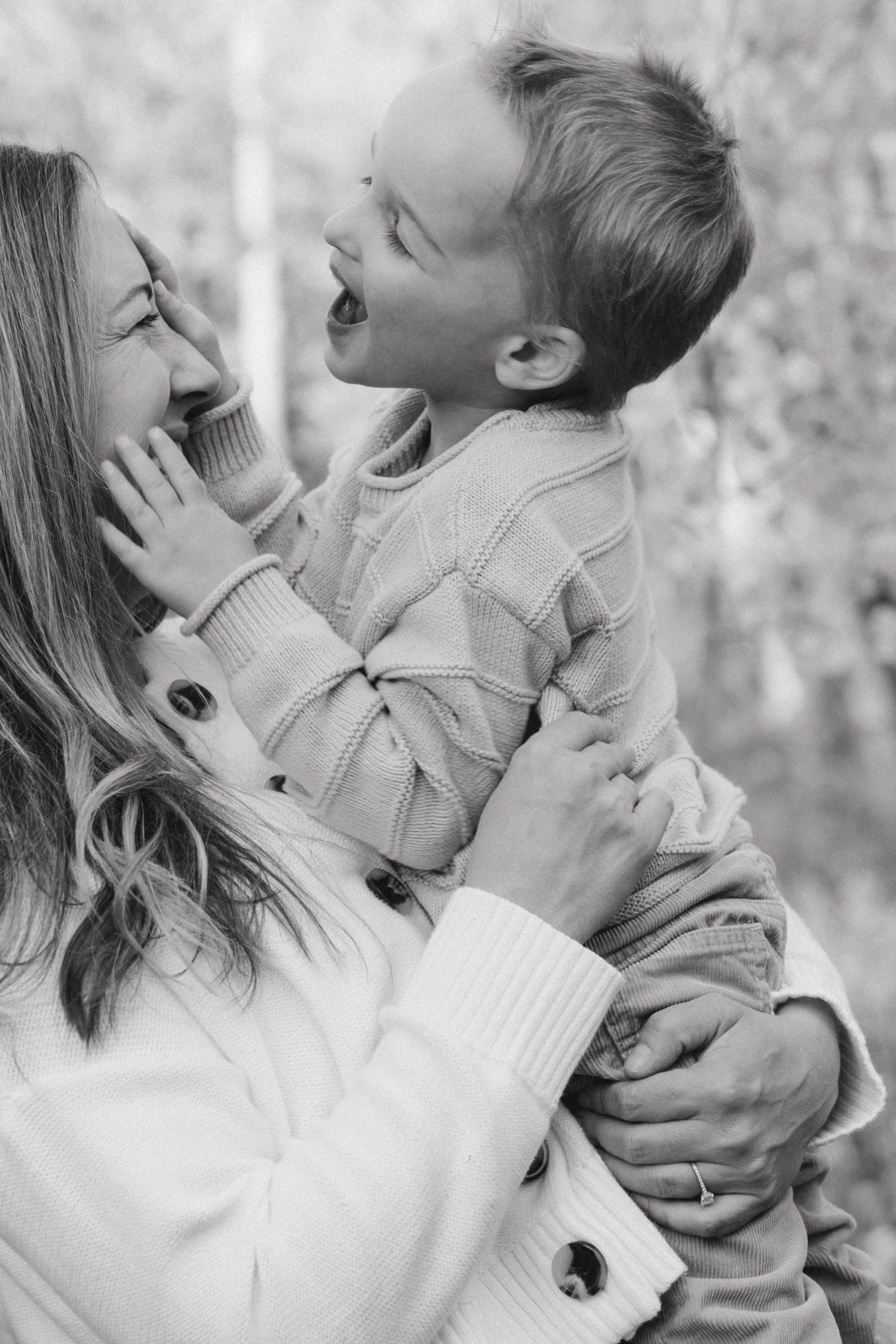 Black and white candid moment of joyful interaction in outdoor setting.