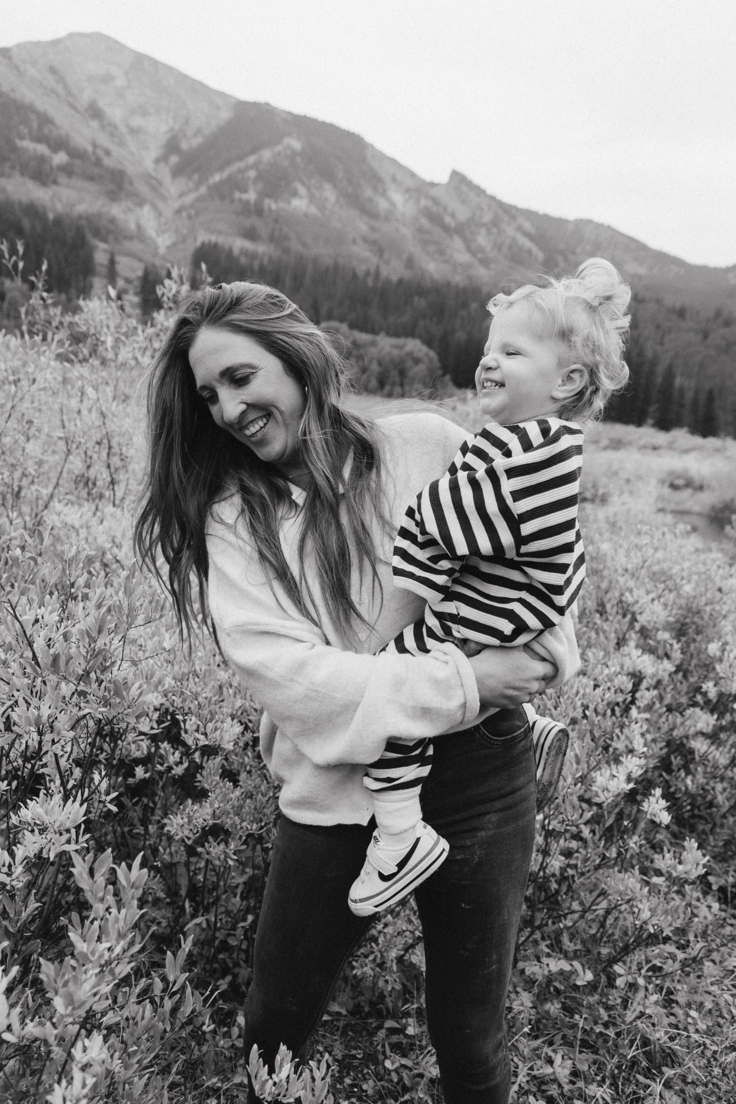 Candid black and white photos of joyful moments in a mountain meadow.