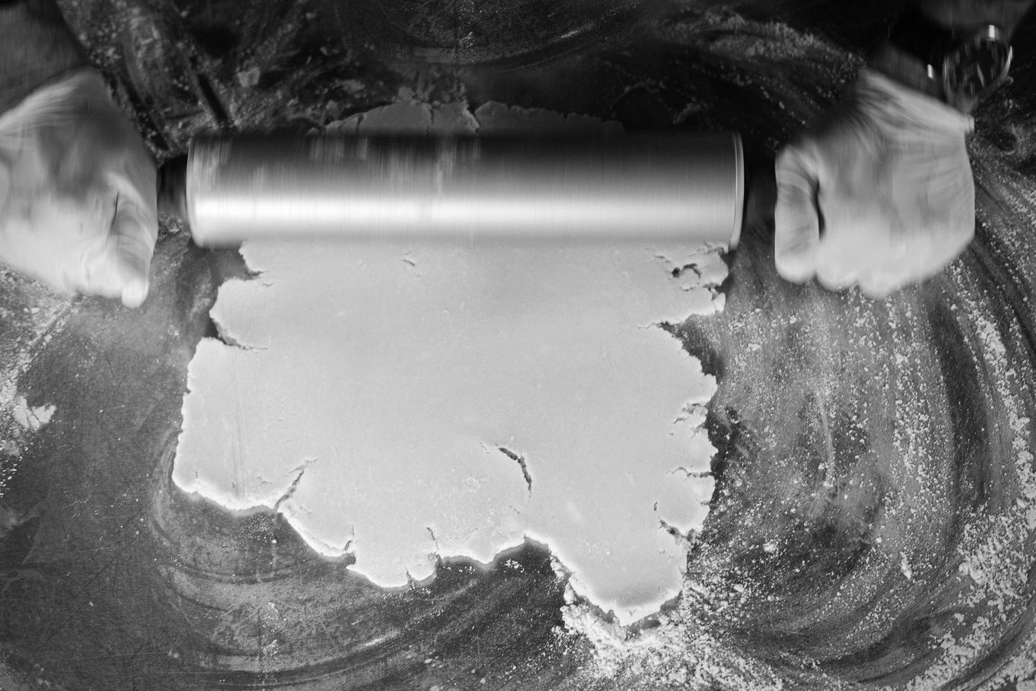 Black and white aerial photograph shows a dramatic volcanic eruption with billowing smoke and ash clouds rising skyward.