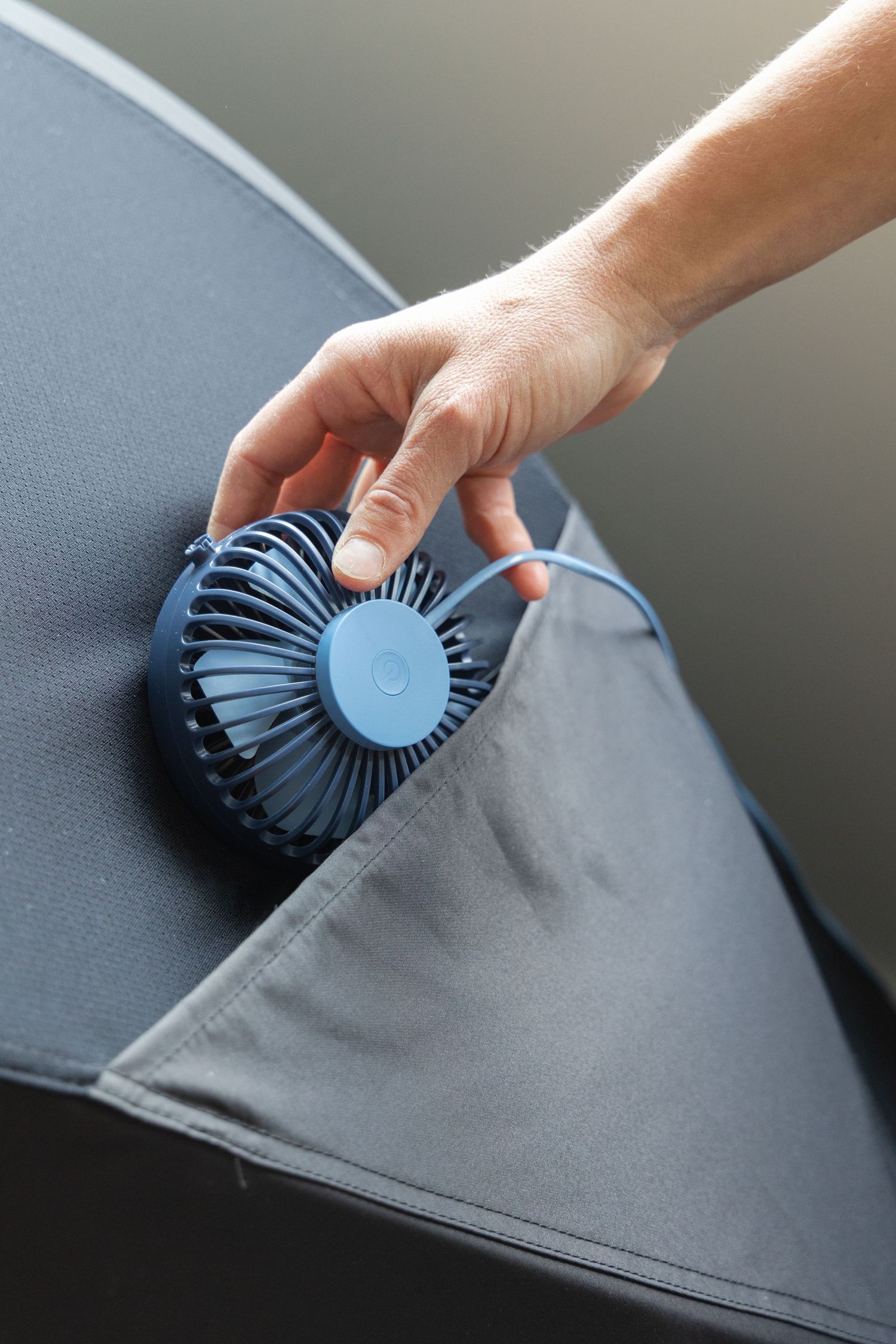 A hand demonstrates cleaning a car's interior fabric upholstery using a round brush attachment tool.