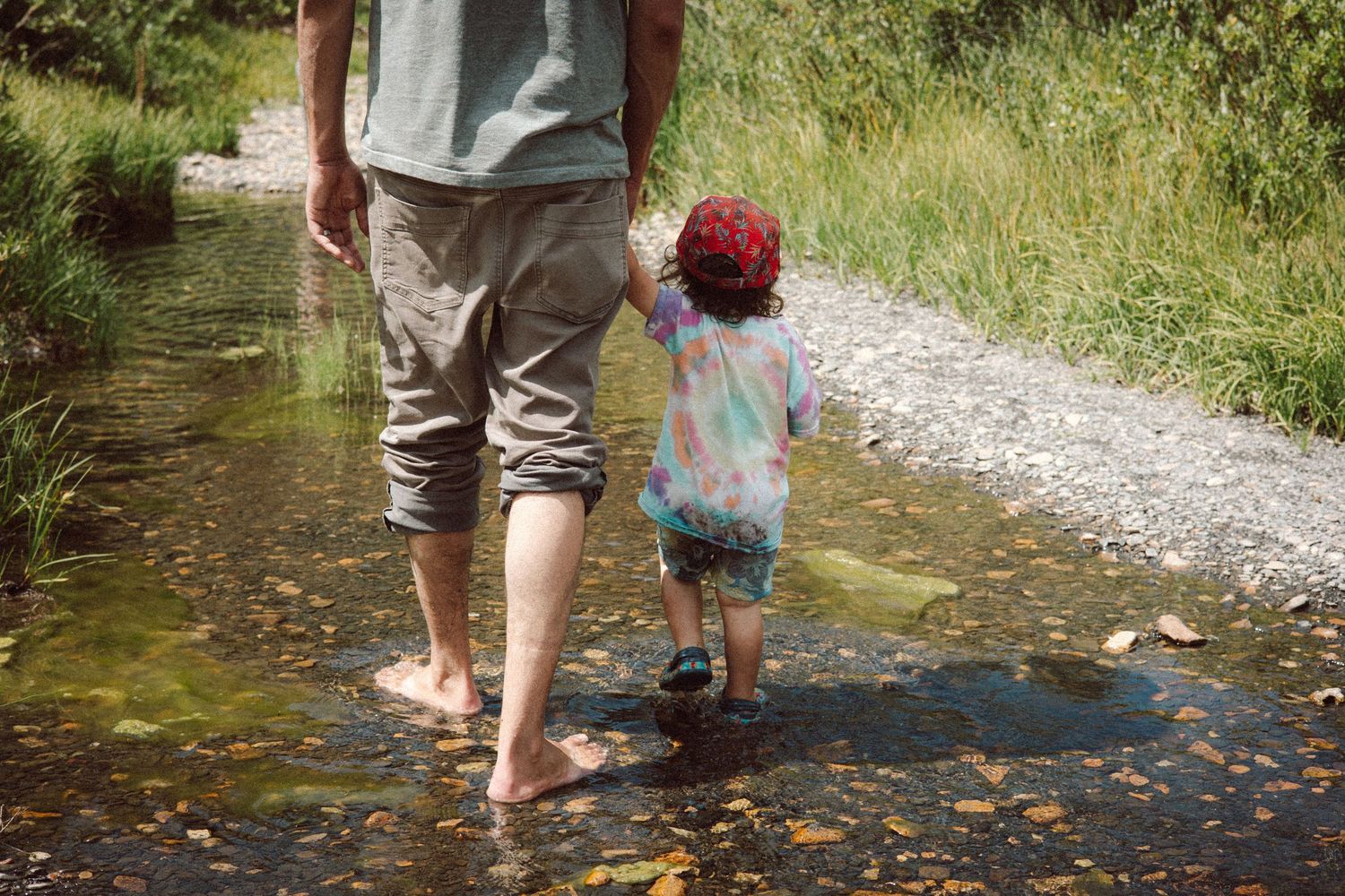 People wading and playing in a shallow stream on a sunny day.