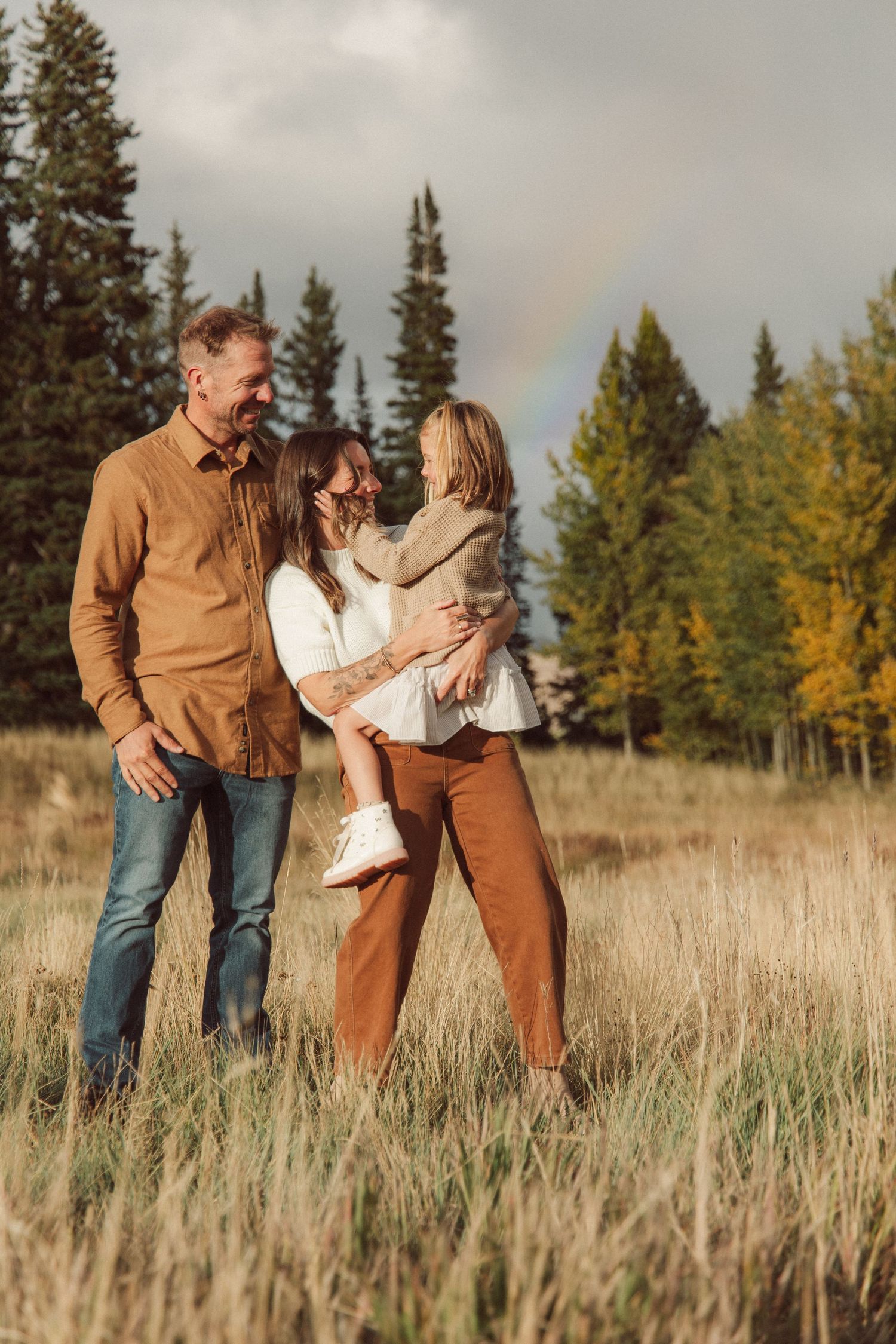 Fall family photo Crested Butte, CO with golden aspens and mountain views ski lifts rainbow