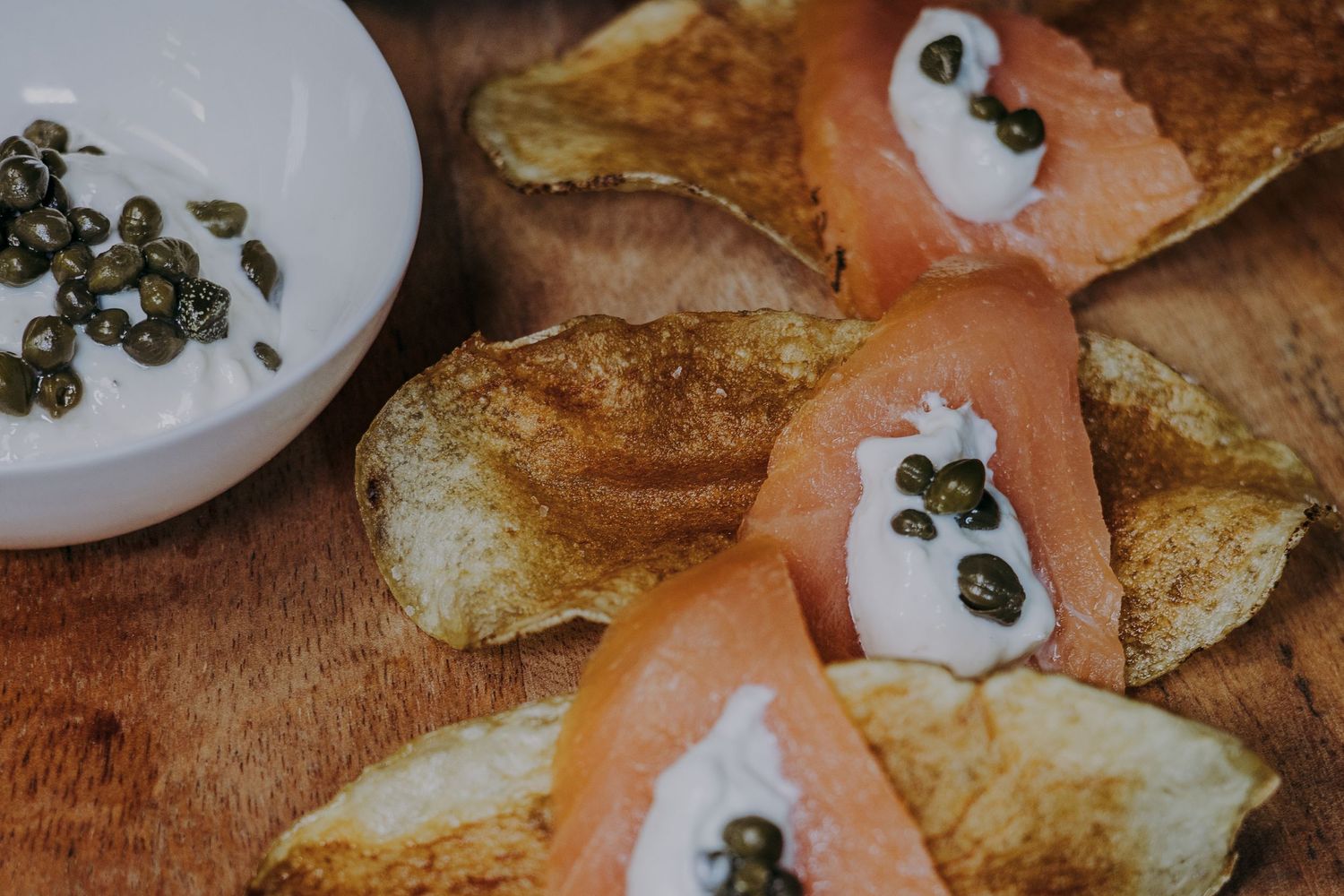 Smoked salmon appetizers with cream cheese and capers served on crispy bread slices.