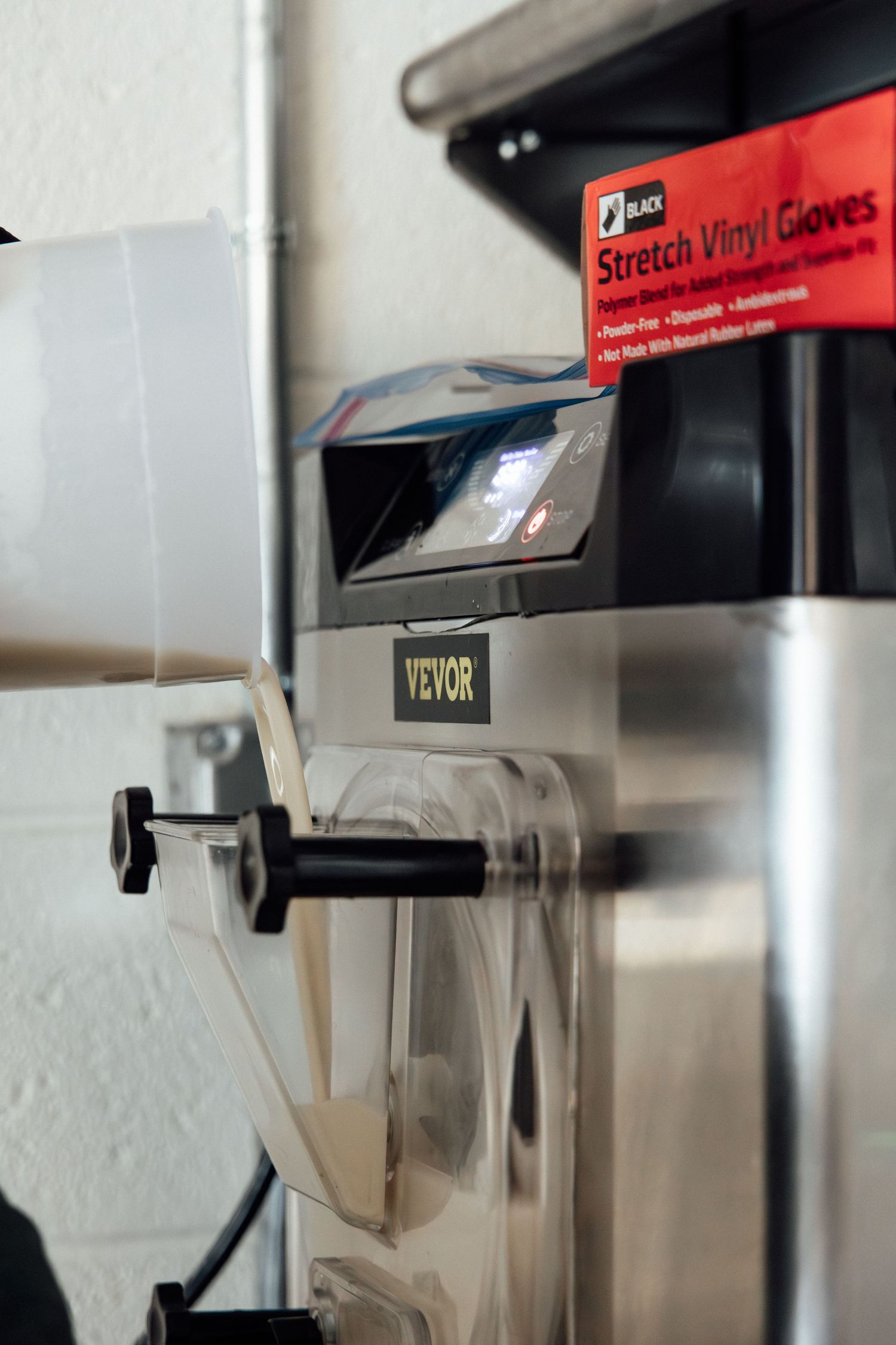 VEVOR machine with Black stretch vinyl gloves box on top, used in a professional or industrial setting.