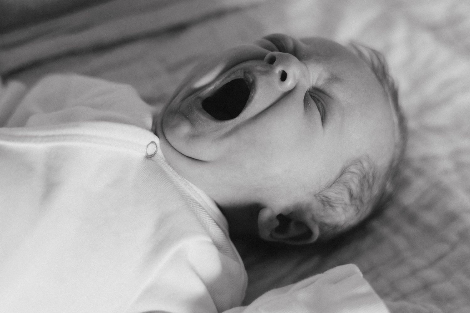 At home newborn photography on bed. Crested Butte, Colorado baby yawning