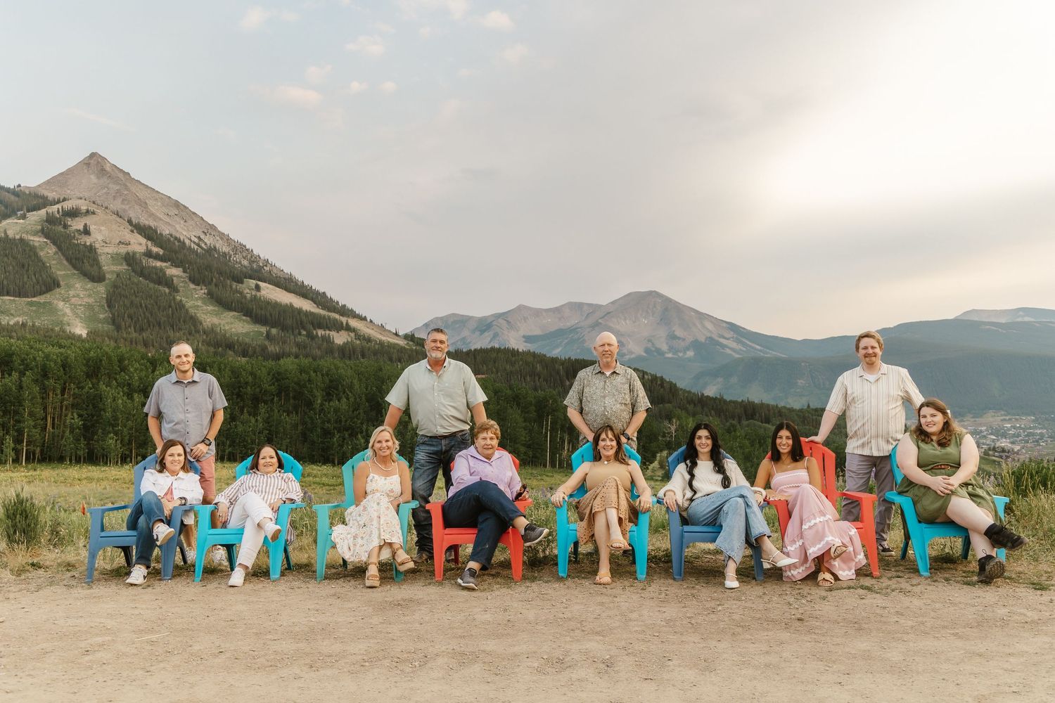 Family gathering photographed against scenic mountain backdrop with colorful summer attire.
