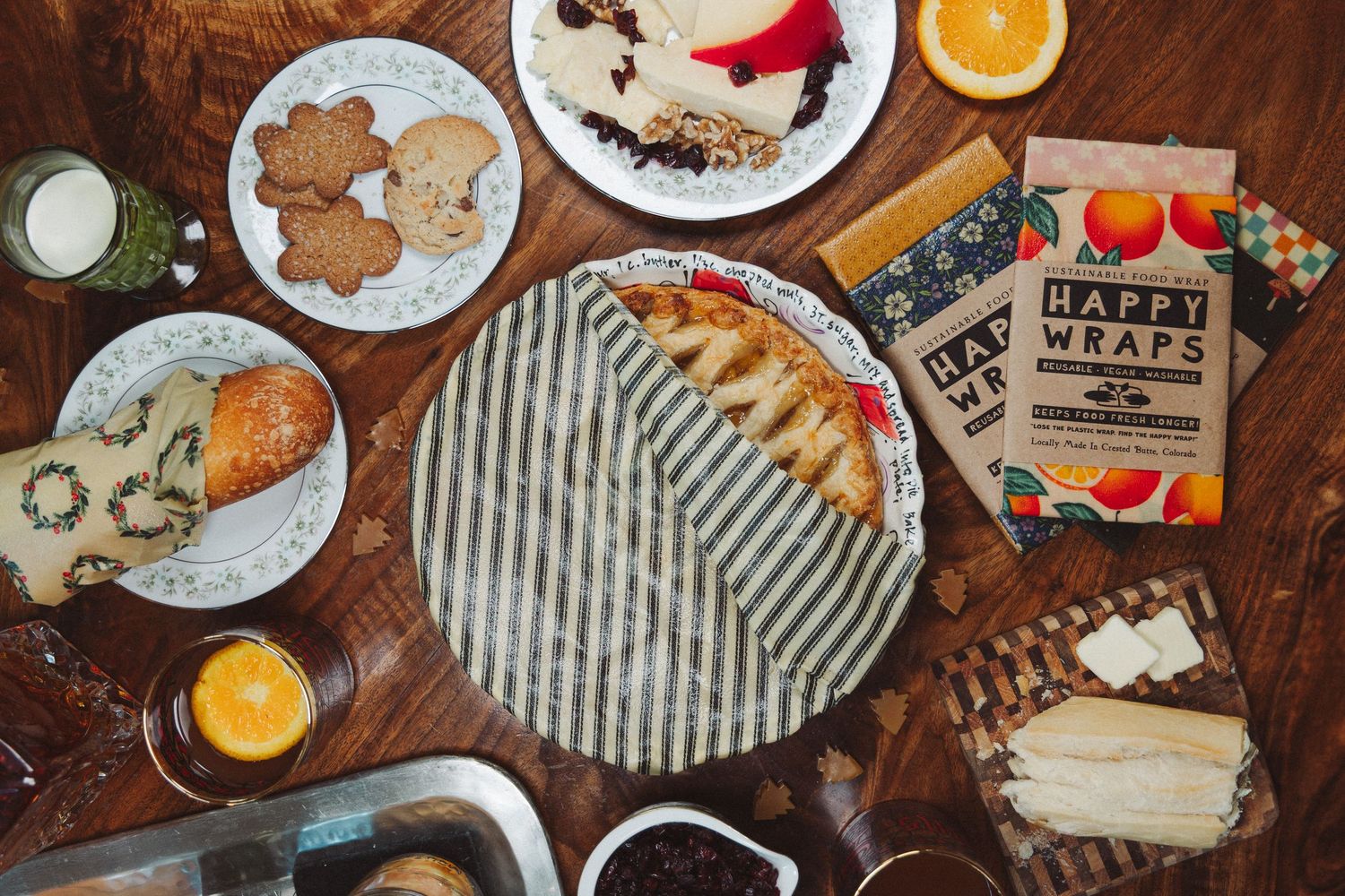 Overhead view of Christmas baking ingredients and gingerbread cookies on a rustic wooden table with scattered flour.