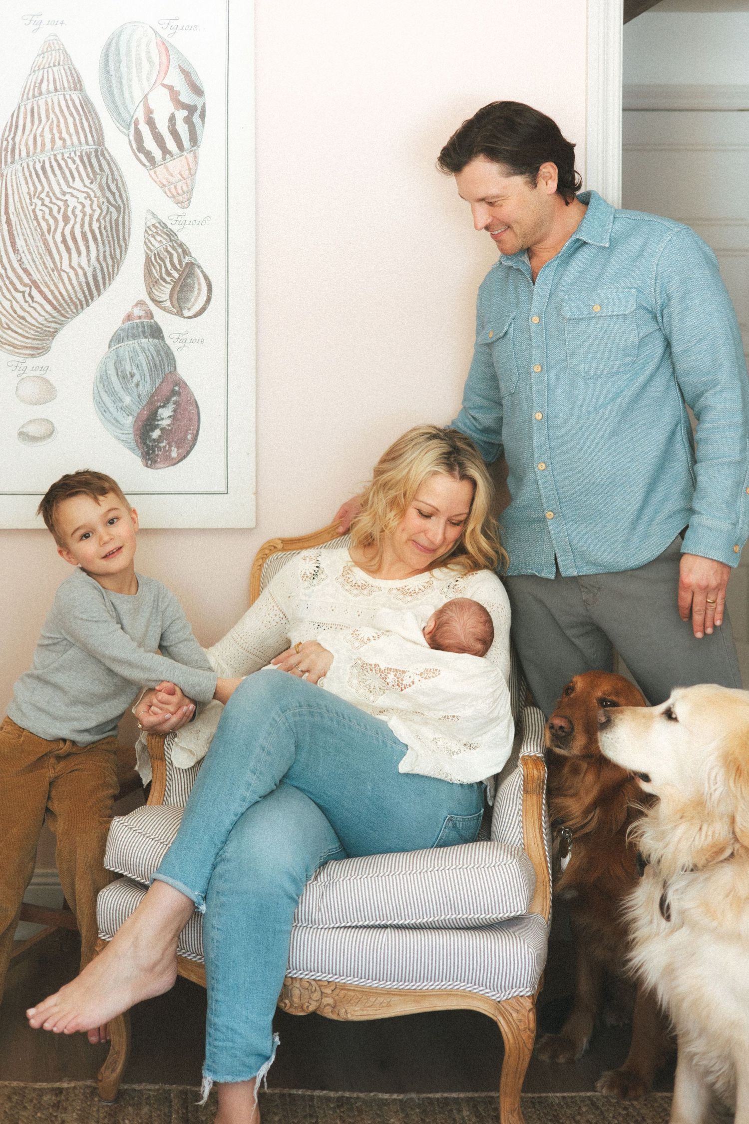 Family and dog share playful moments on a grey couch with zebra artwork in the background.
