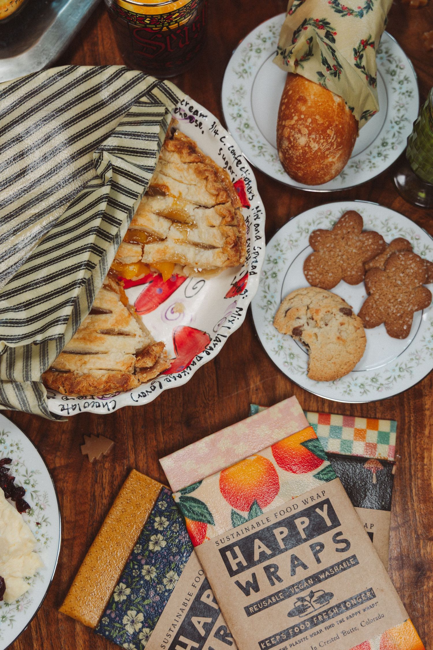 Overhead view of homemade cookies and baked goods with decorative wrapping paper on a rustic wooden table.
