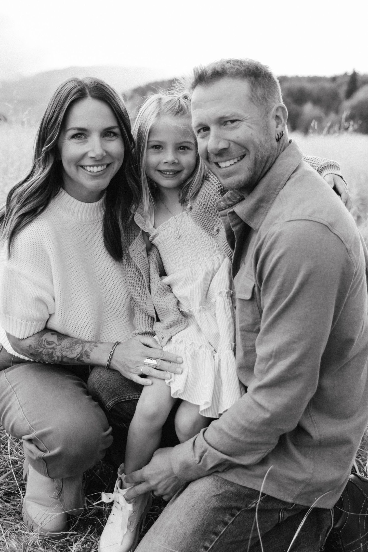 Black and white family portrait series showing joyful embraces and candid moments outdoors in casual attire.