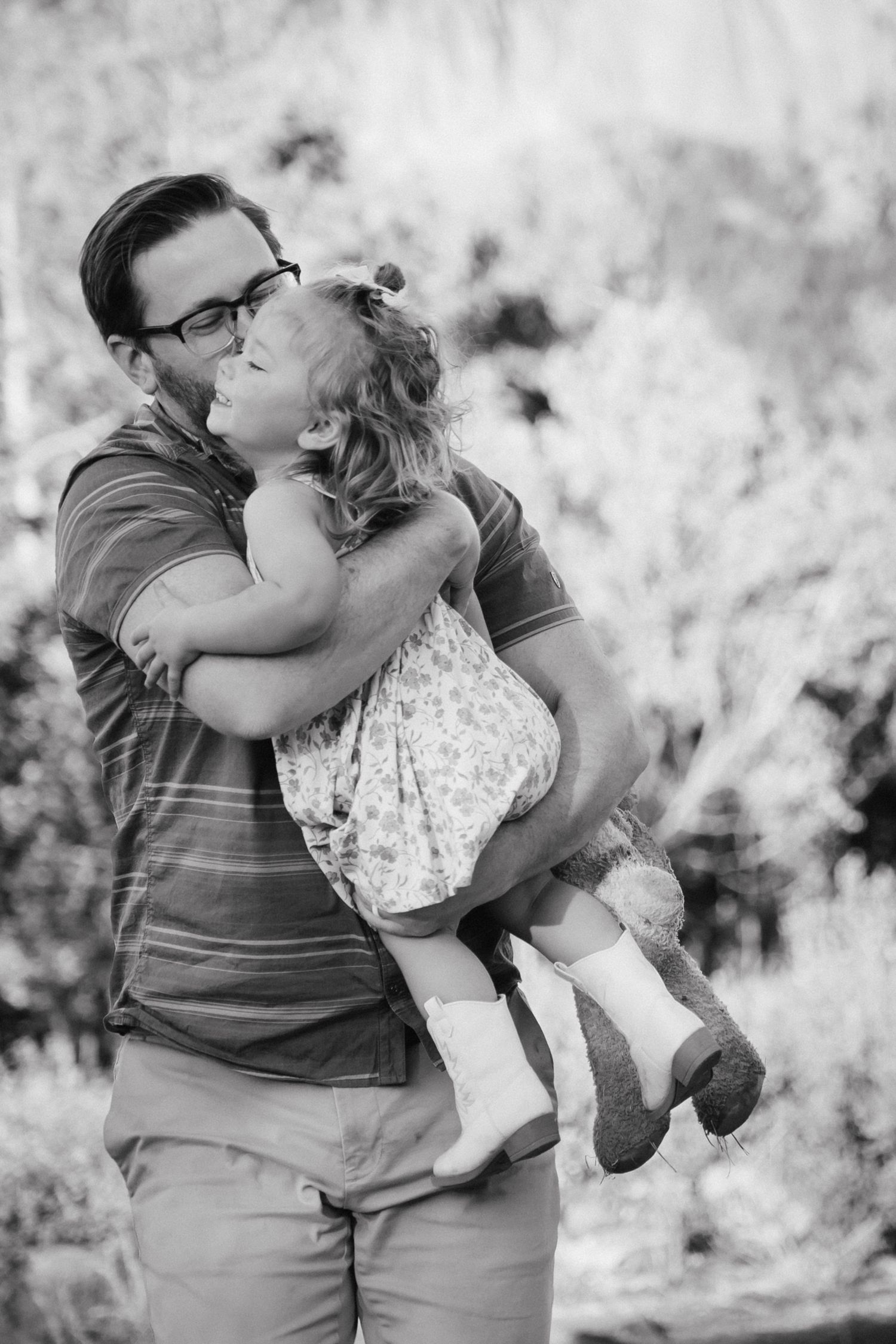A tender black and white moment between parent and child captured outdoors.