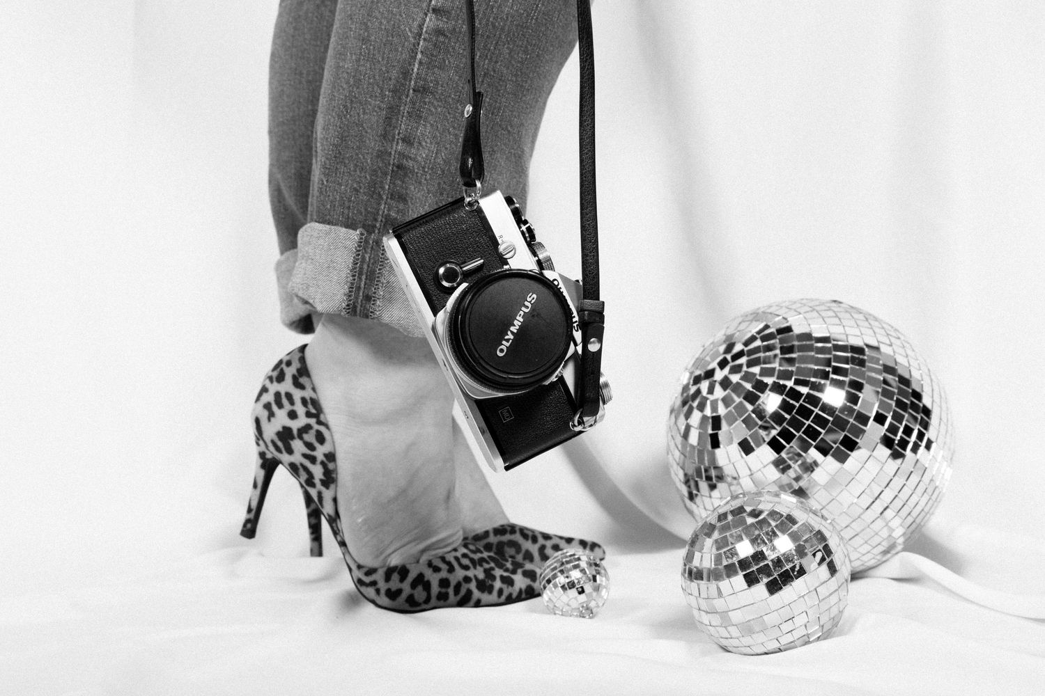 Shiny disco balls in various sizes reflect light against a white background, creating a glamorous party atmosphere.