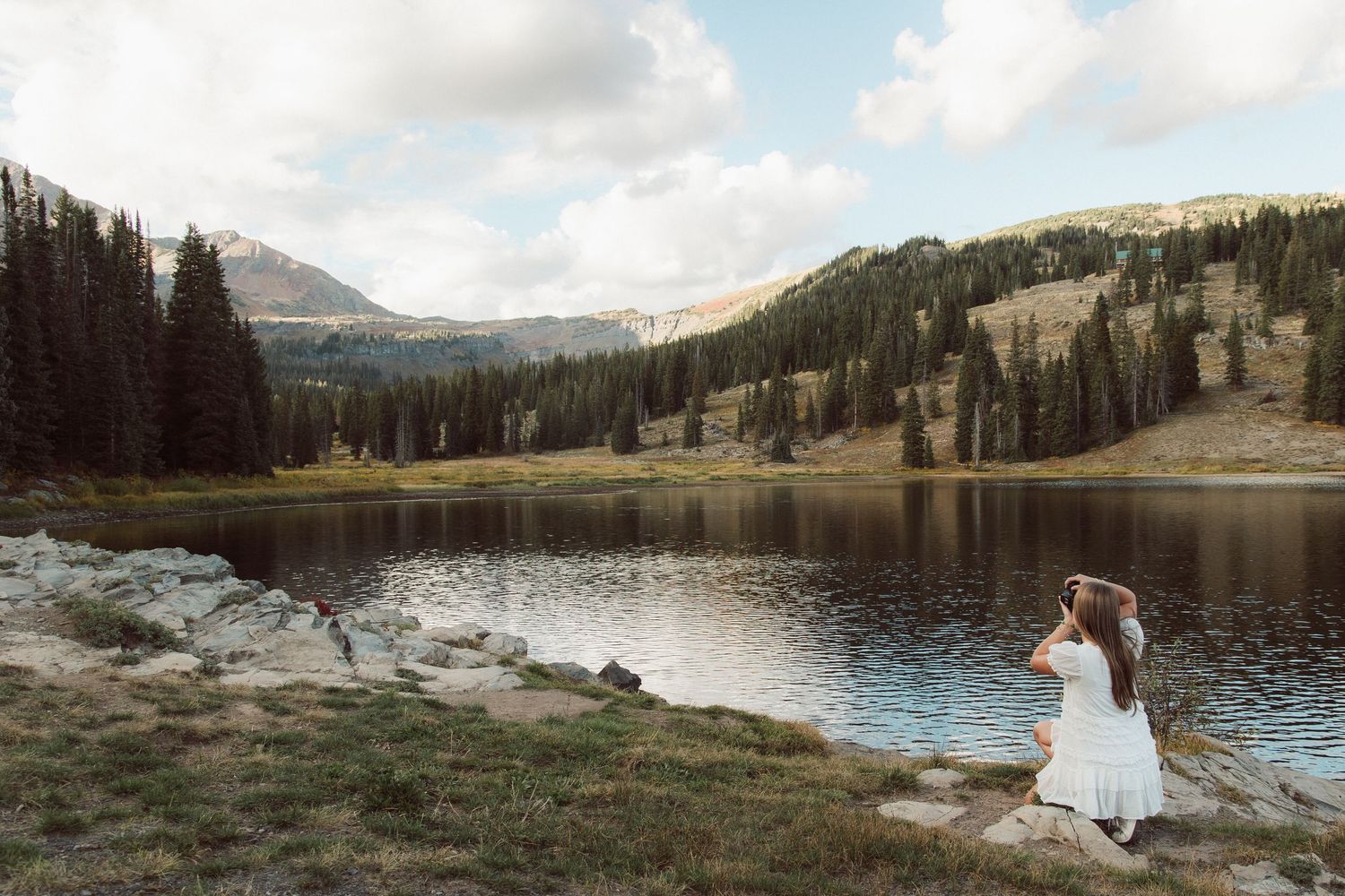 Scenic mountain lake landscape with evergreen forests and rocky shoreline.