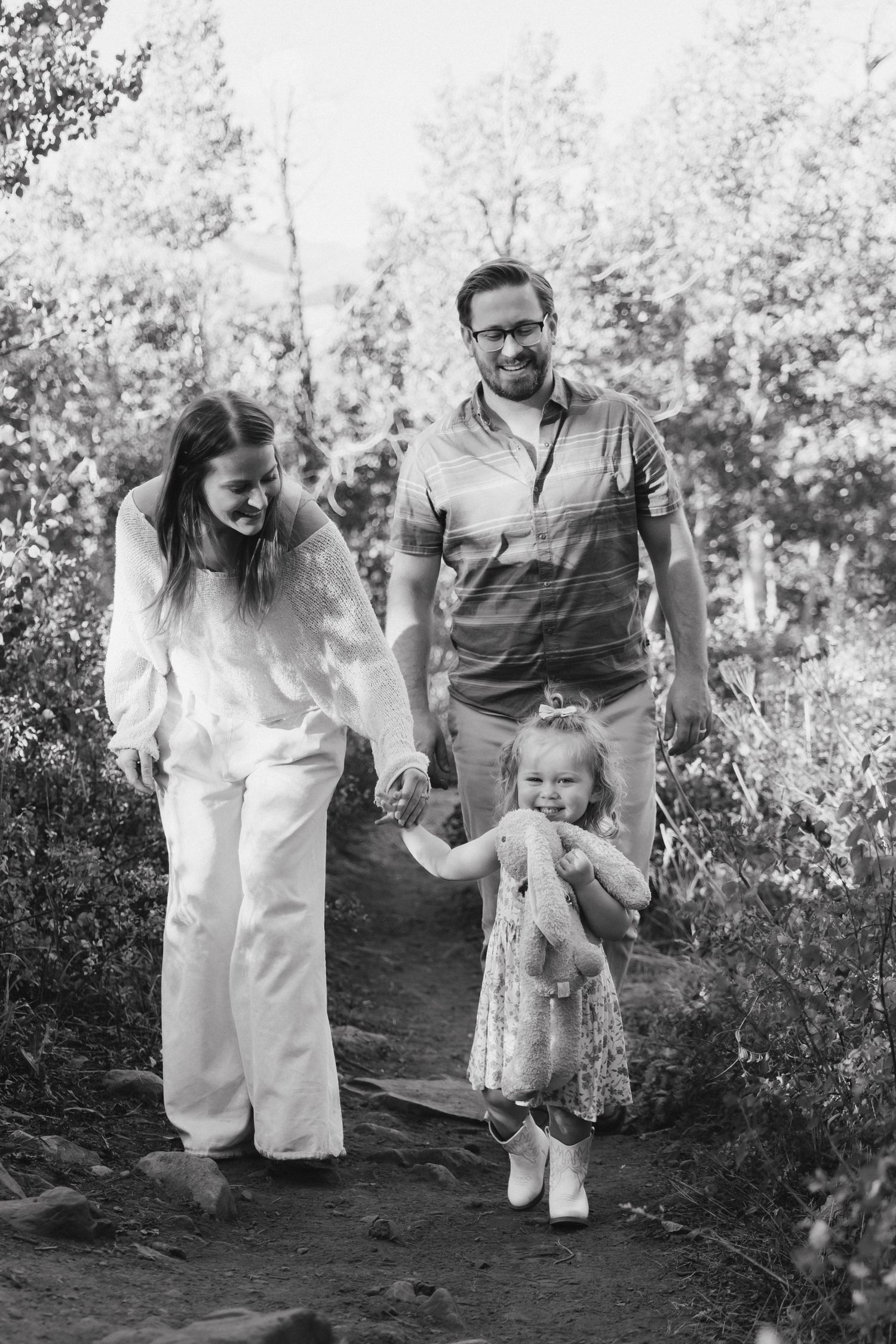 Family walking together outdoors in a natural setting with trees in the background.