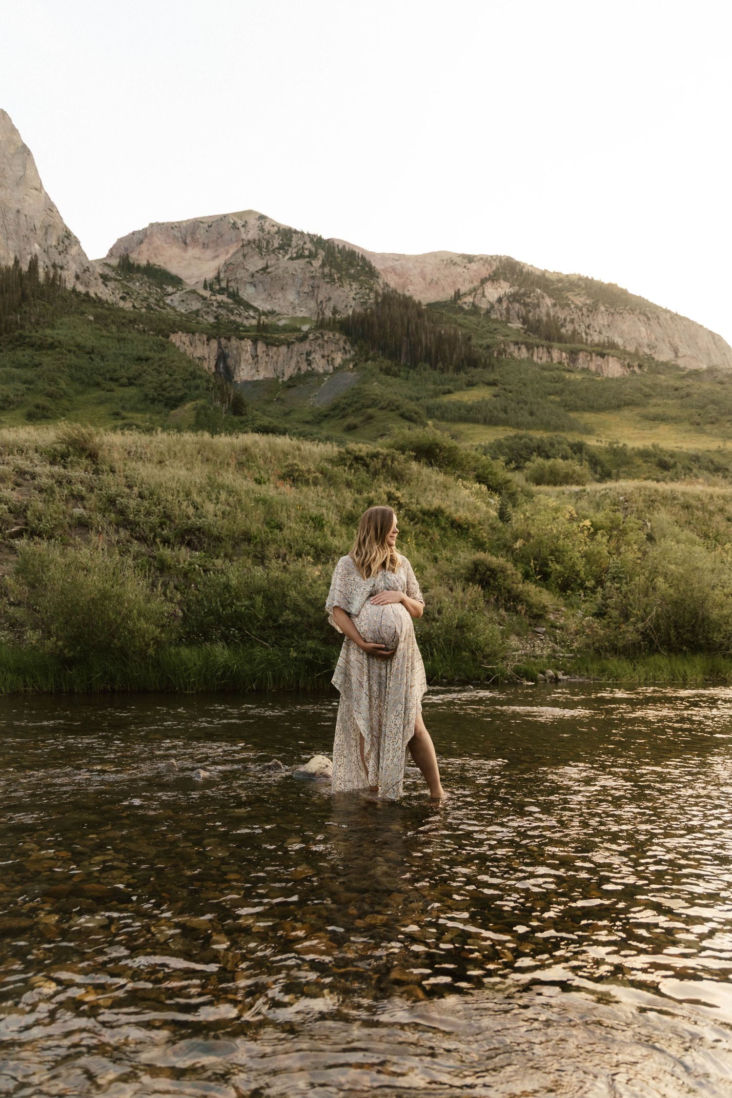 Romantic scene at a mountain lake with dramatic cliffs and golden sunset light reflecting on the water.