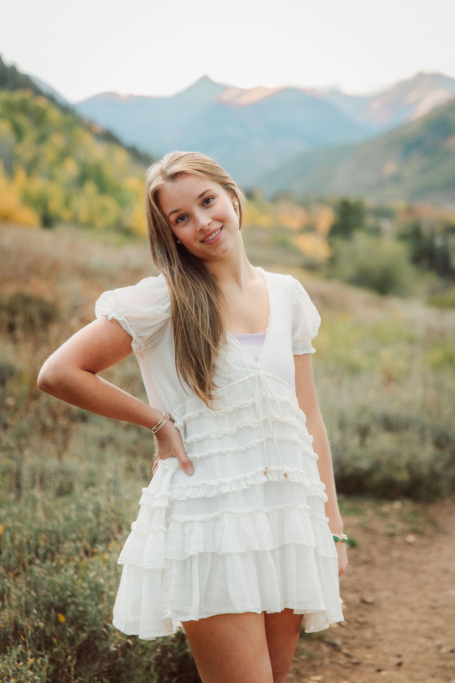 White ruffled dress photographed against mountain backdrop during golden hour outdoor photoshoot.