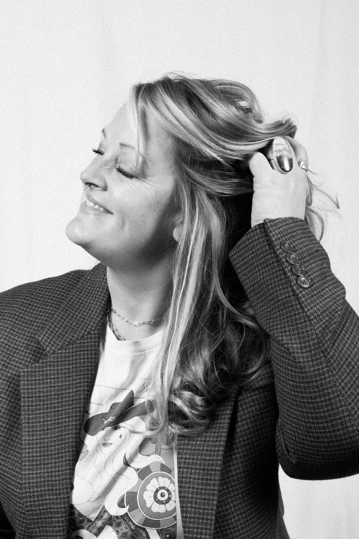Black and white photo series showing person with blonde hair in checkered blazer making expressive poses.