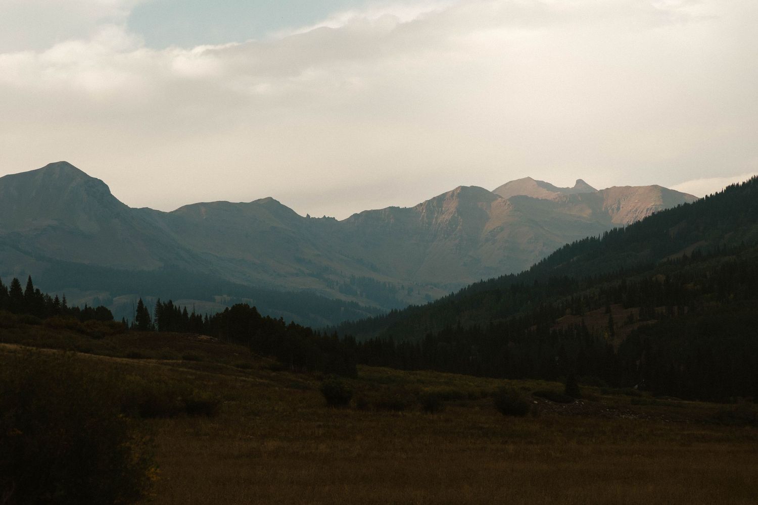 Scenic mountain landscape with rolling hills under cloudy sky.