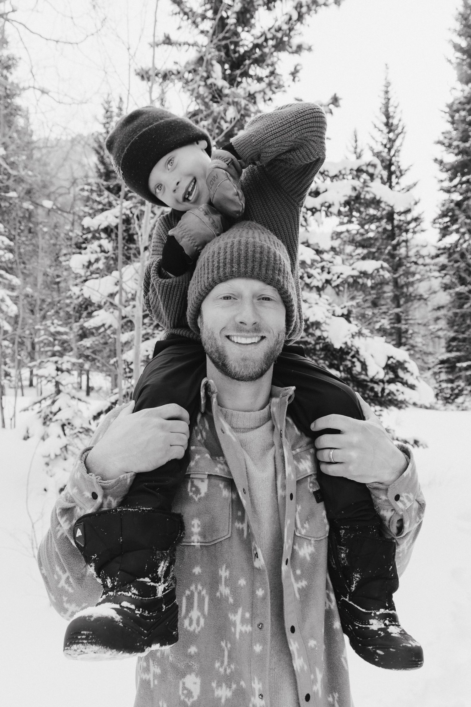Two people enjoying a playful moment in the snowy winter forest while wearing warm winter clothing.