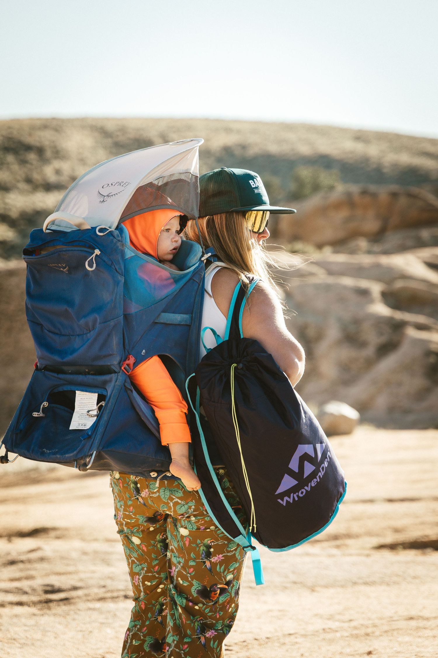 Hiker with backpacks standing in a desert landscape against rocky terrain and clear sky.