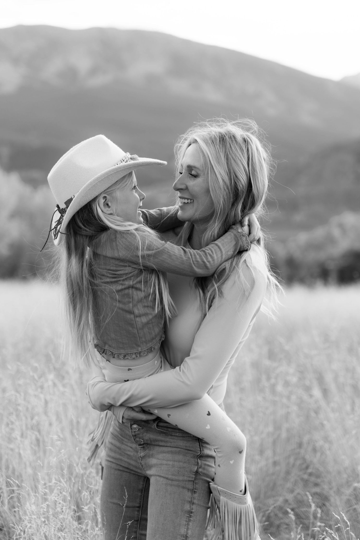 Black and white photos capture intimate moments between a couple embracing in a serene meadow setting.
