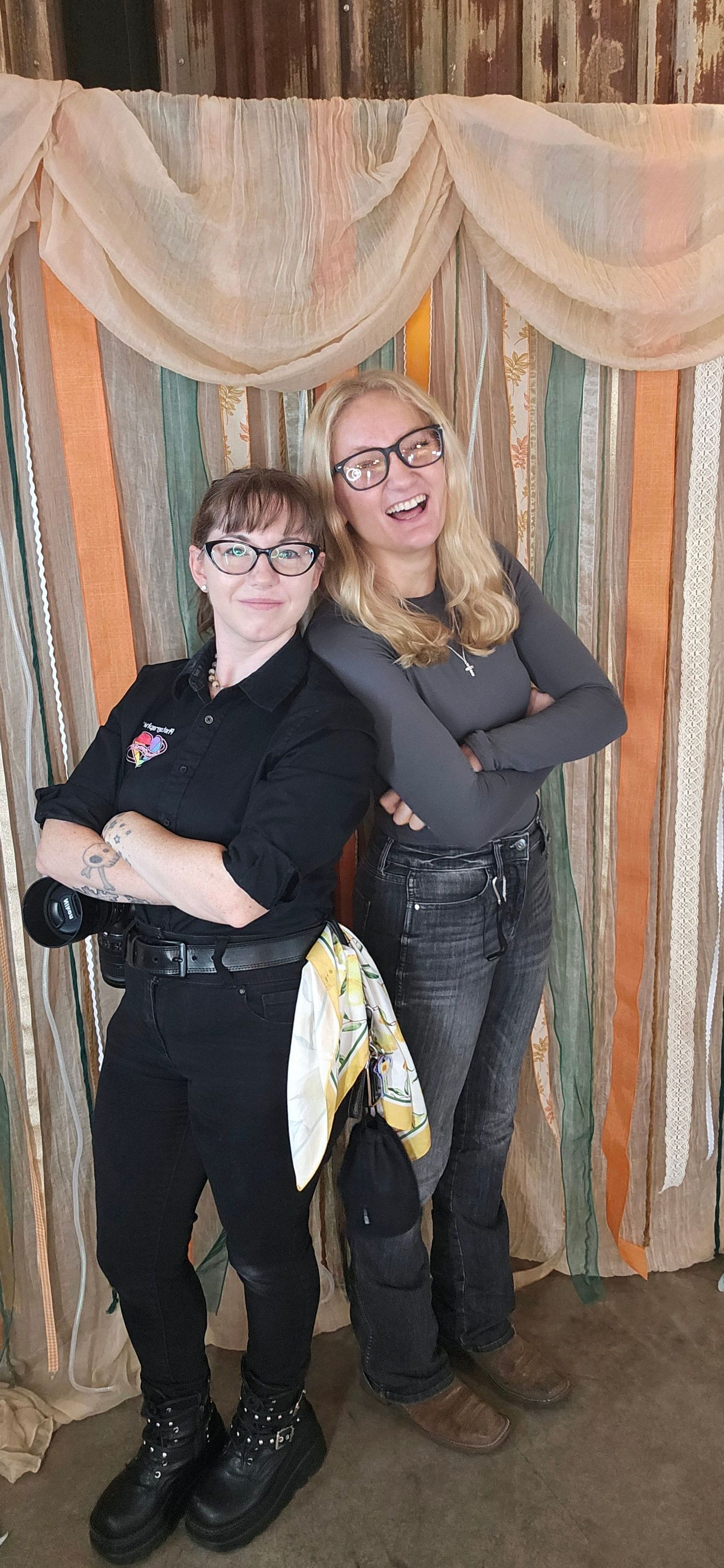 People posing together against a wall decorated with hanging fabric strips in neutral tones.
