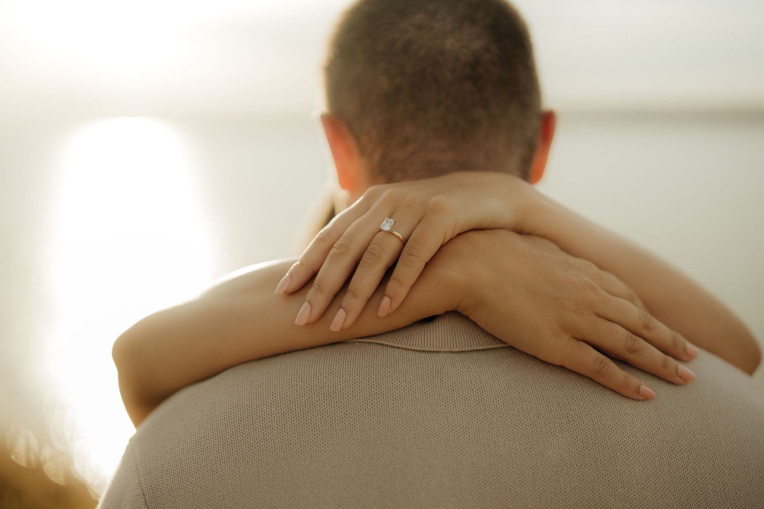 Hands gently caressing bare shoulders and back in a tender, intimate moment.