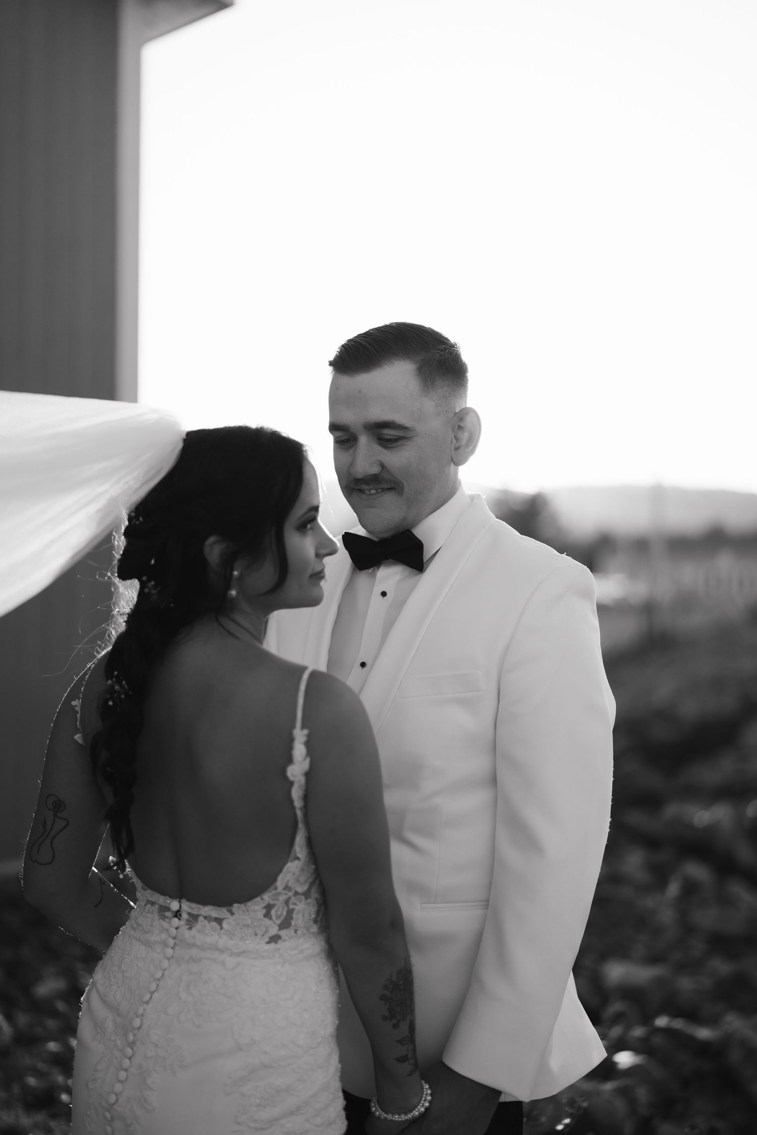 A romantic black and white photo series showing a couple in wedding attire embracing outdoors.