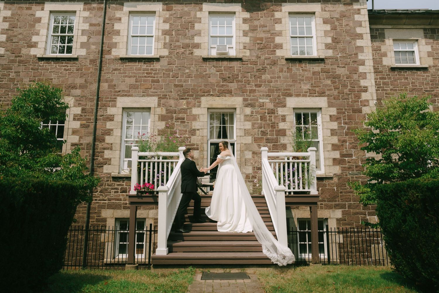Historic stone building serves as elegant backdrop for flowing white wedding dress and veil.