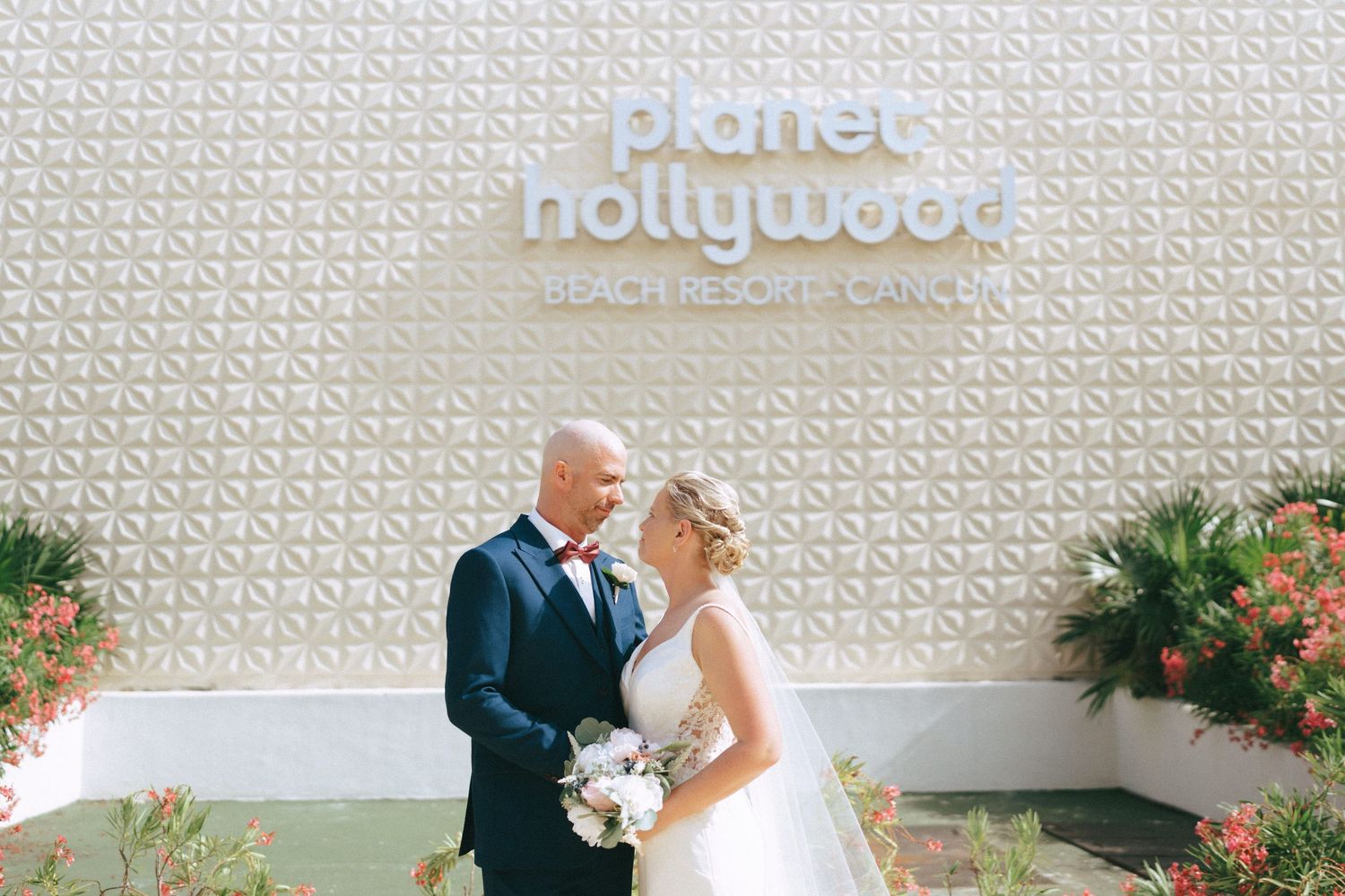 Wedding couple posing for photos against a modern textured wall with resort signage.