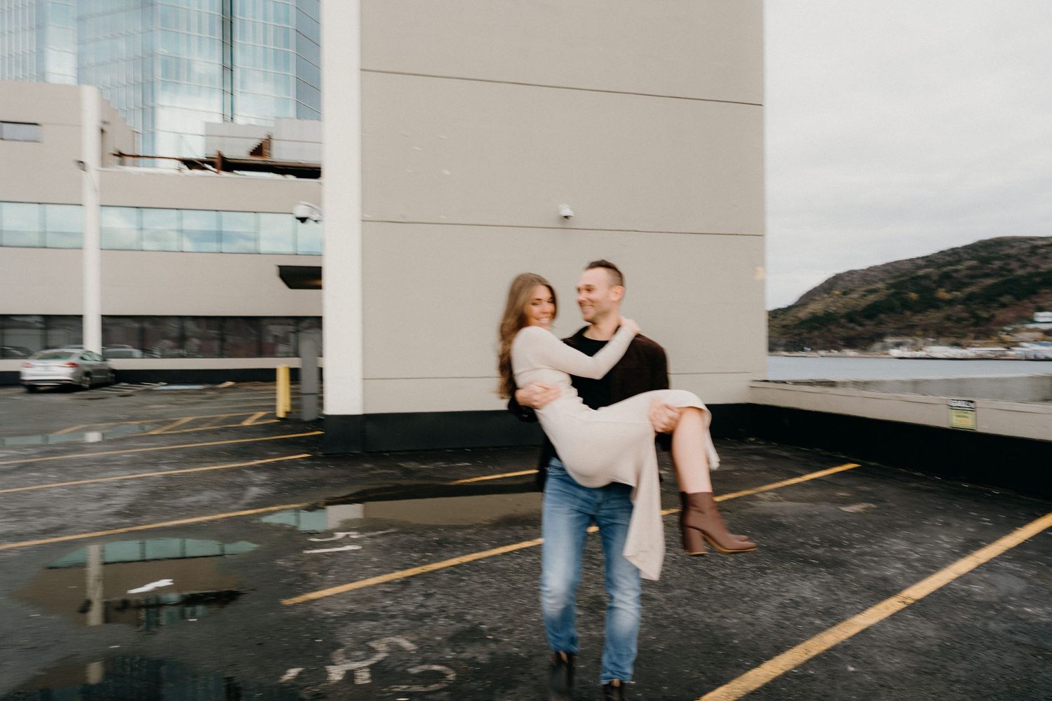 Playful rooftop engagement photography with coastal scenery in the background.