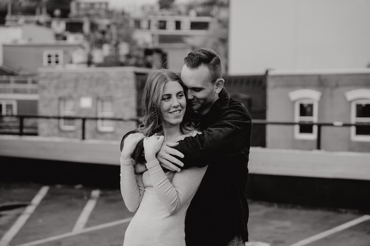 Joyful couple laughing together during rooftop photography session in urban setting.