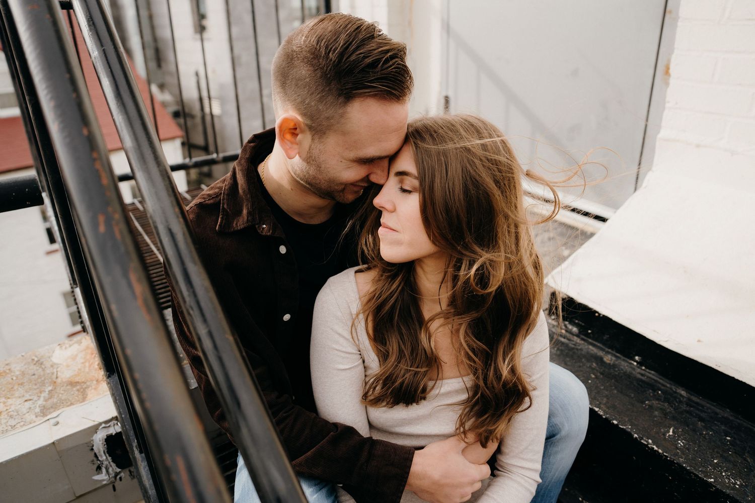 Couple sharing tender moments during lifestyle photoshoot on city rooftop.