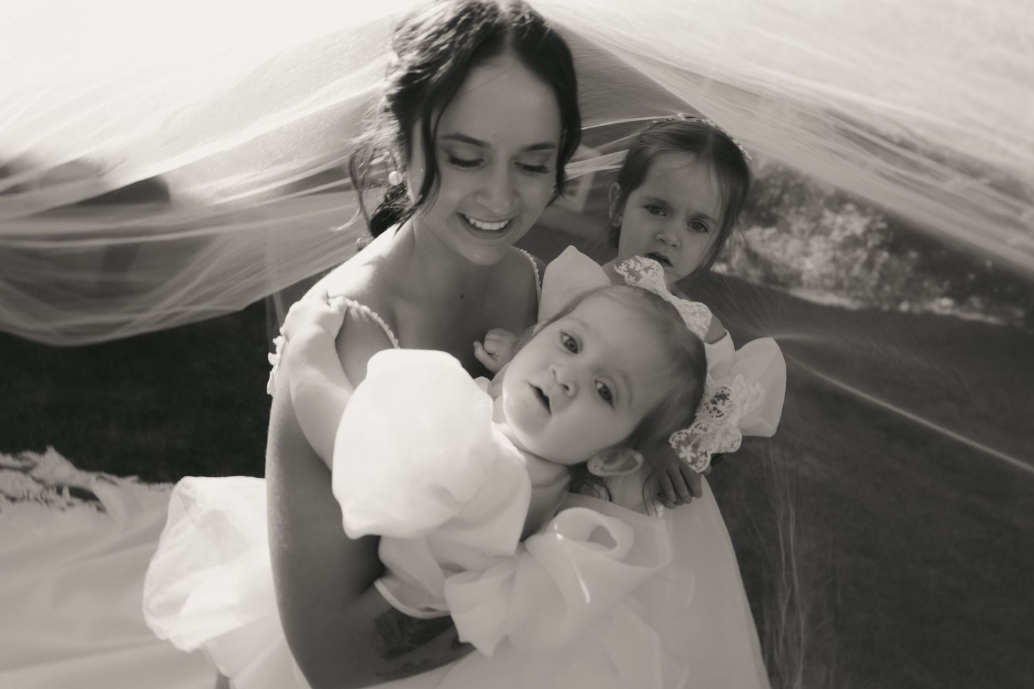 A black and white photo series showing tender moments between a parent and child under flowing white fabric.