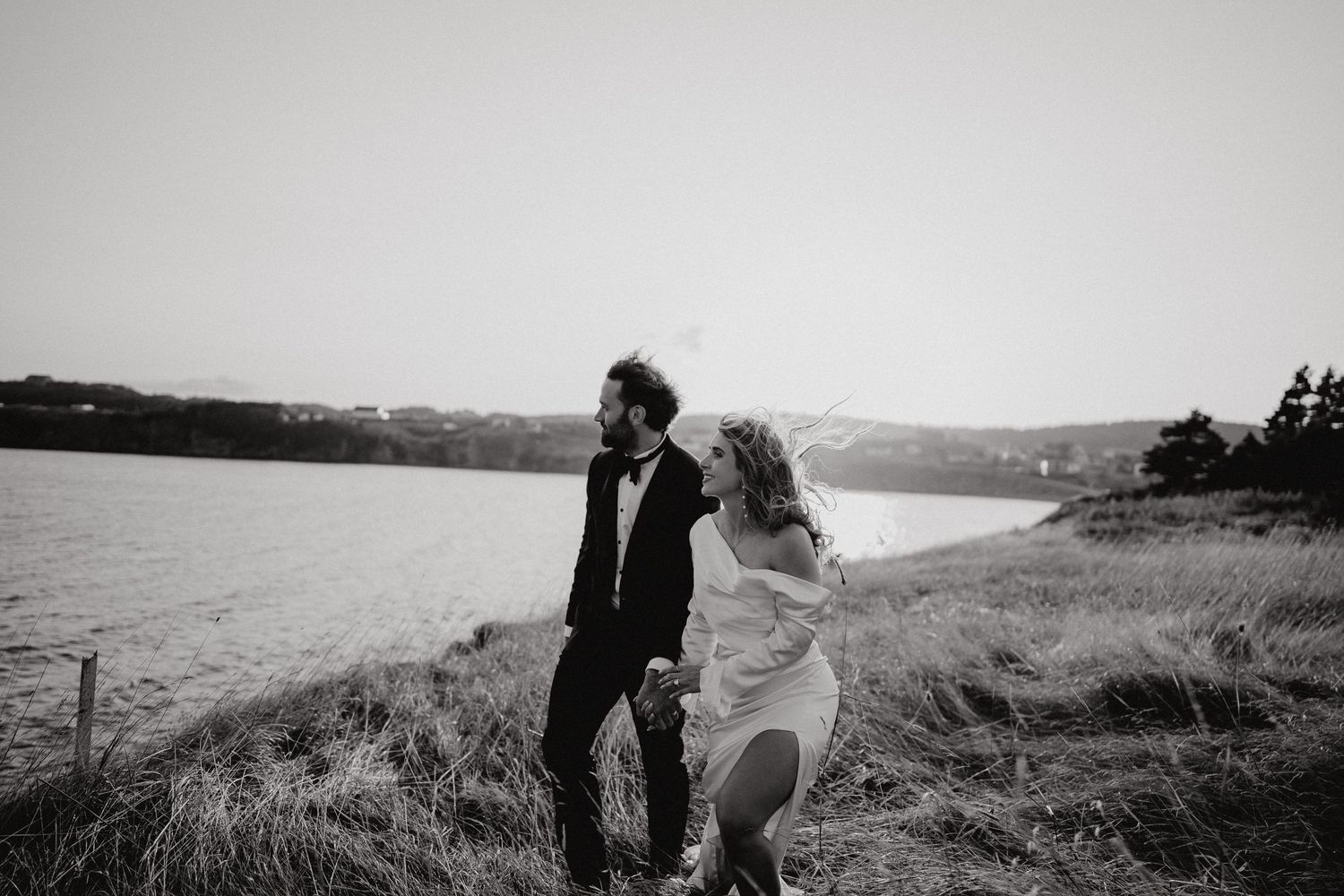 Romantic coastal wedding portraits with dramatic landscape views at sunset.